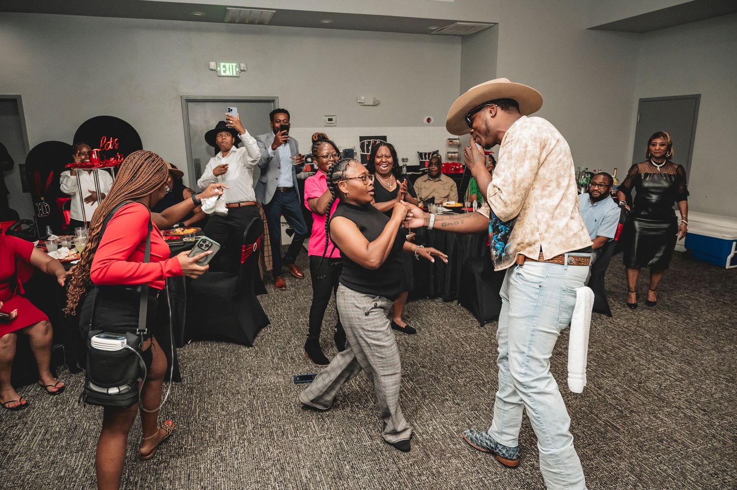 Performer in cowboy hat engages with audience during an energetic indoor event.