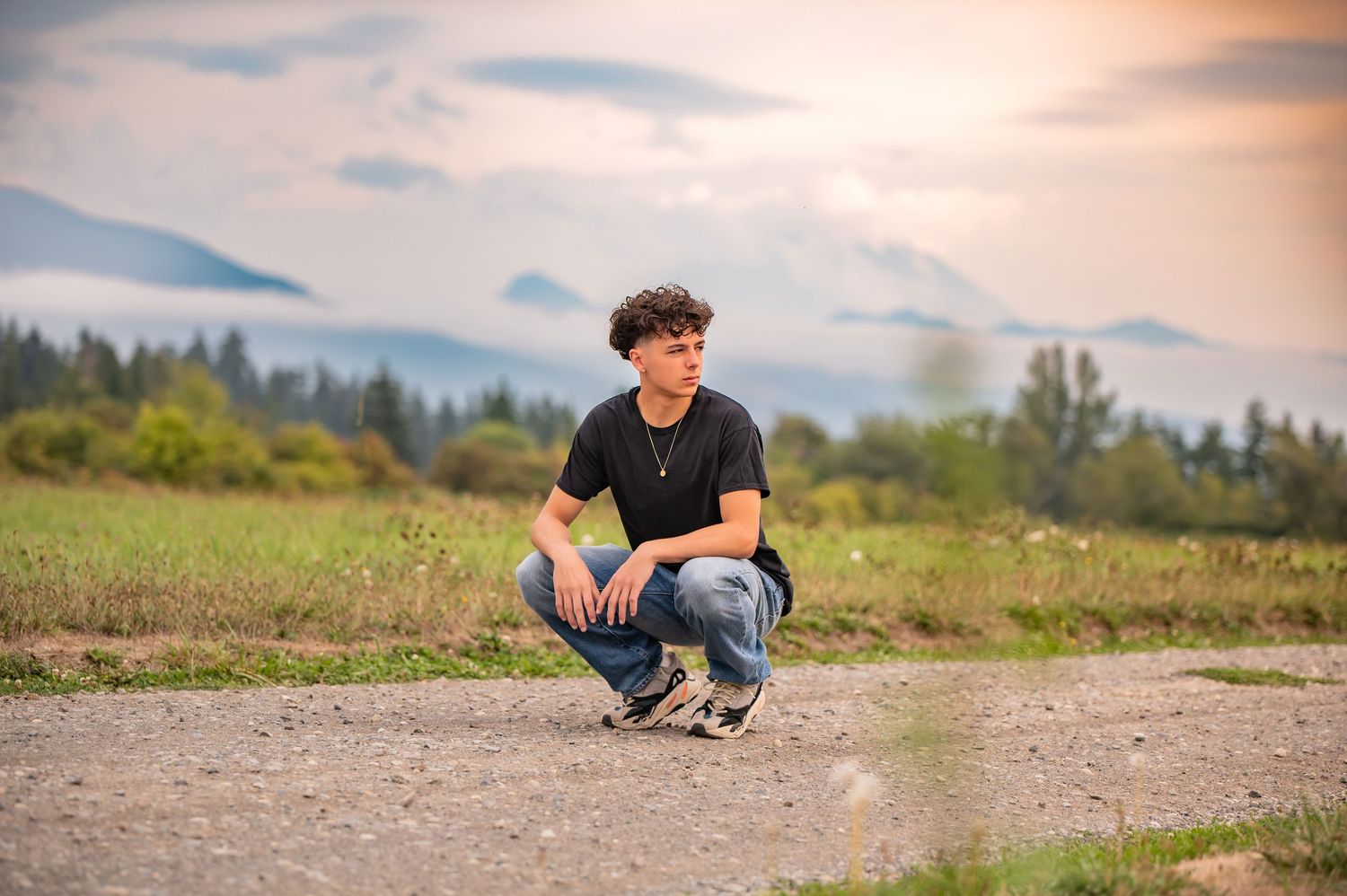Scenic mountain landscape with Tahoma HS Senior posing at sunset on dirt road for senior photos in Enumclaw, WA