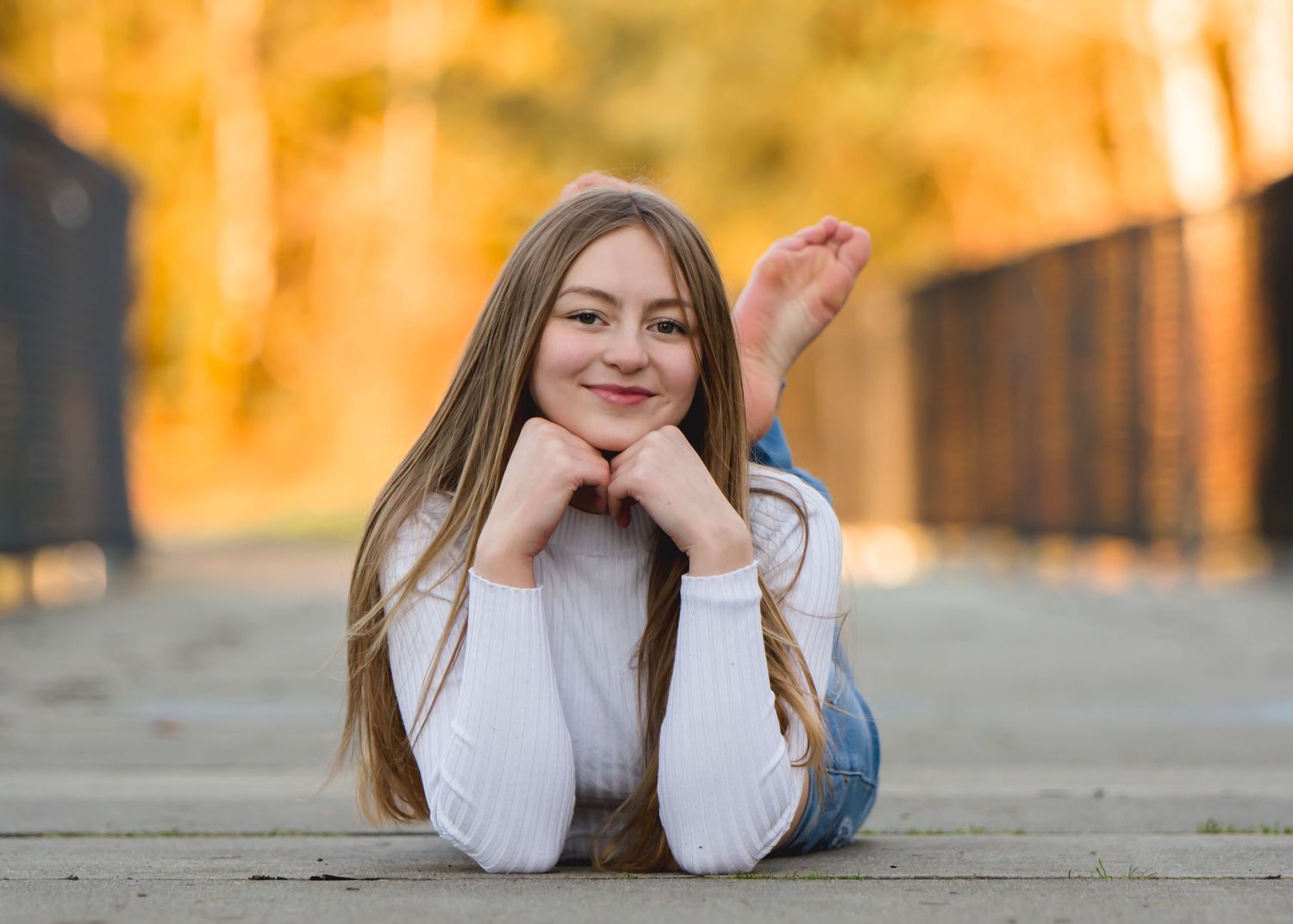 Kent, WA senior lying on a surface with golden autumn lighting in the background during a senior photshoot in Maple Valley, WA