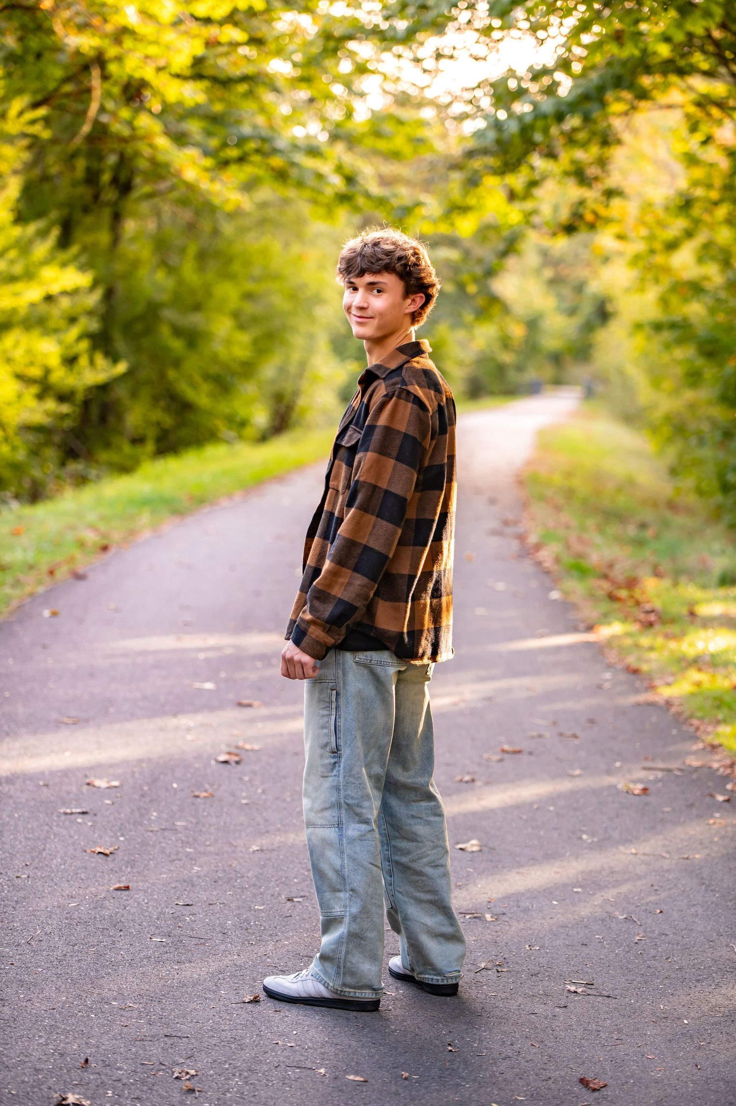 Tahoma senior in plaid flannel and jeans standing on autumn path with golden foliage. Senior Session