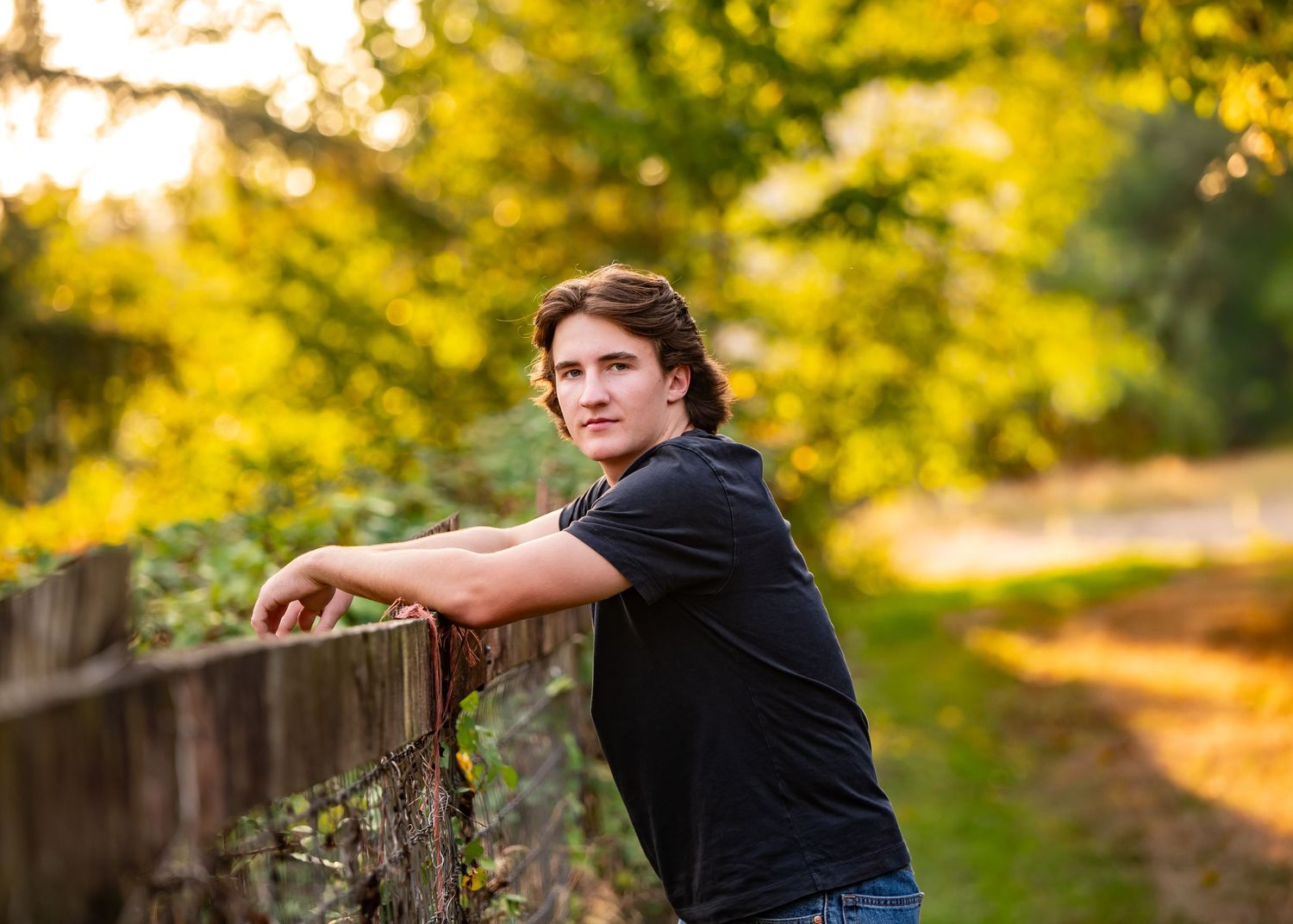 A row of autumn trees with golden leaves creates a scenic backdrop for senior portraits for the Tahoma High School senior