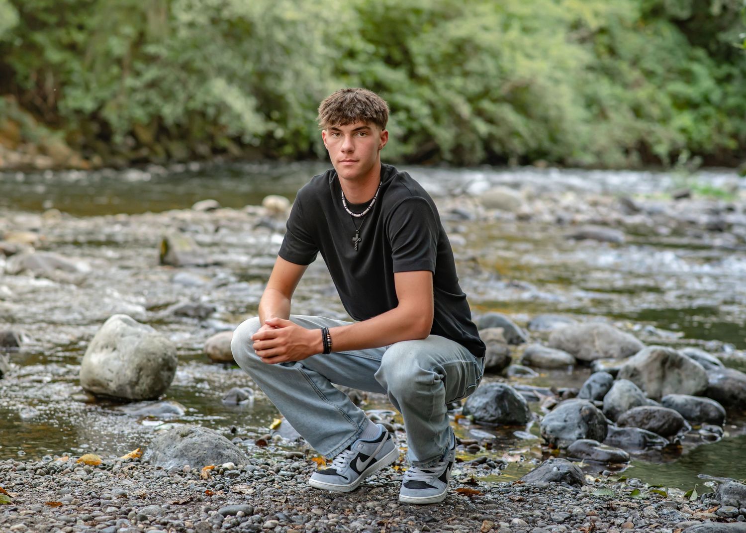 Tahoma HS senior relaxing on rocky riverbank surrounded by nature. Senior Photos