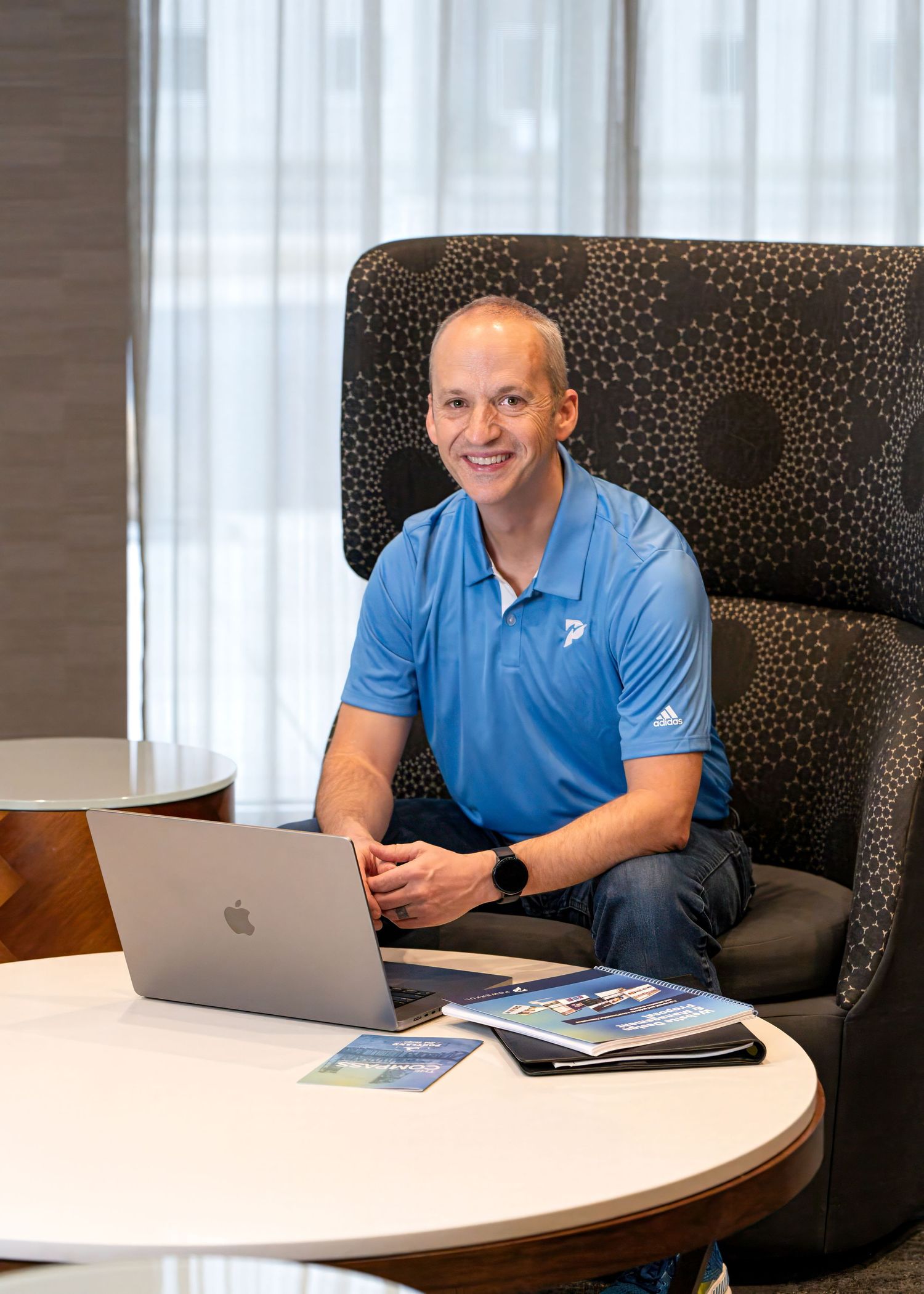Modern office setting with curved conference table and laptop workspace. Man poses for a corporate branding session in Pullman, WA