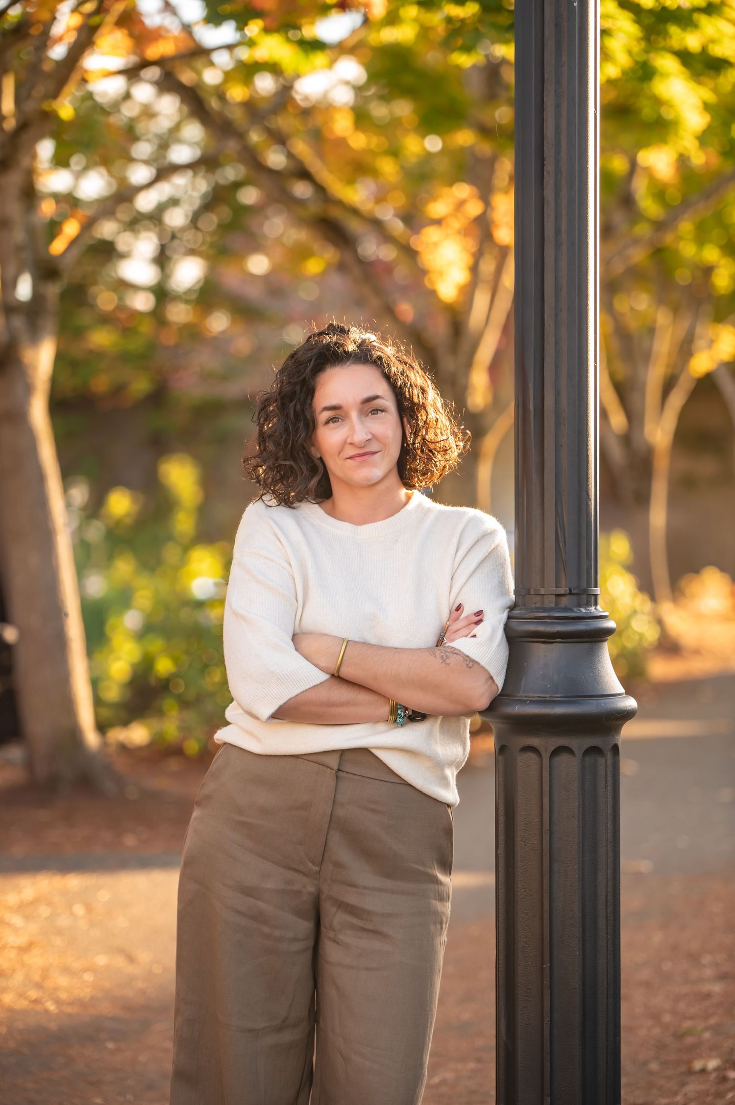 Professional portrait session in a park with autumn foliage and warm lighting against a black lamppost in Enumclaw, WA