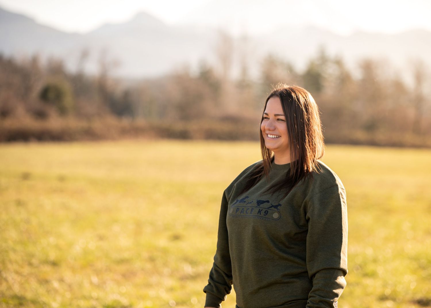 Person in olive sweatshirt standing in golden field during sunset for a branding session in Enumclaw, WA.