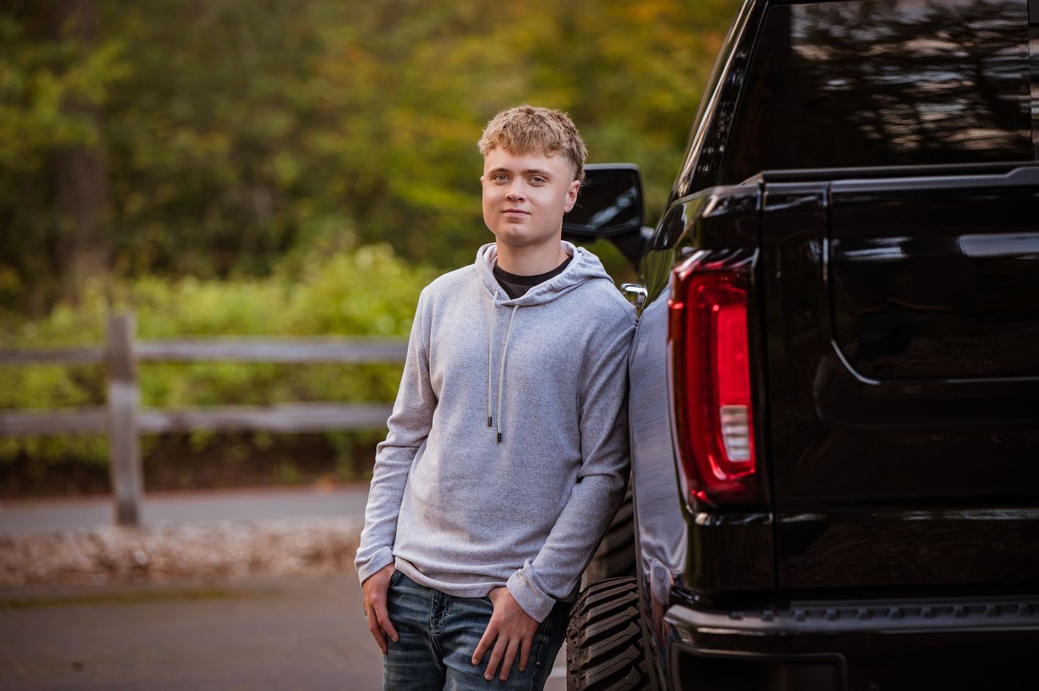 Casual portrait of a Tahoma senior next to black pickup truck in parking lot. Maple Valley, WA