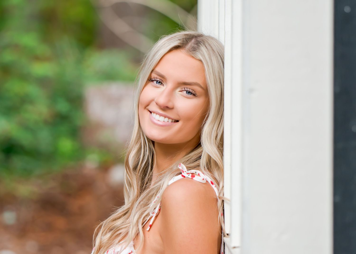 Professional outdoor portrait session featuring bright natural lighting and white architectural elements.