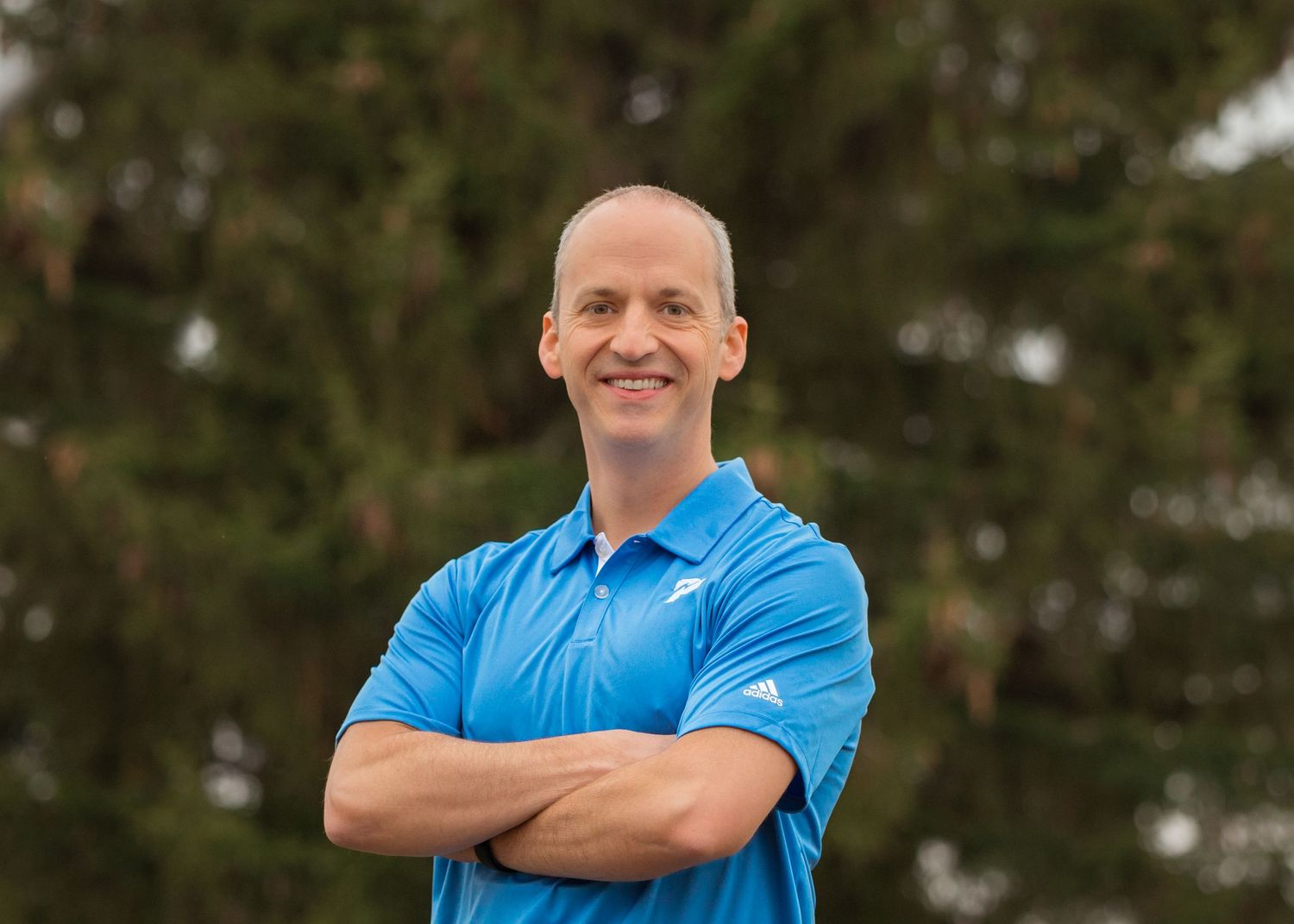 Professional headshot in a blue polo shirt against an outdoor background in Pullman, WA