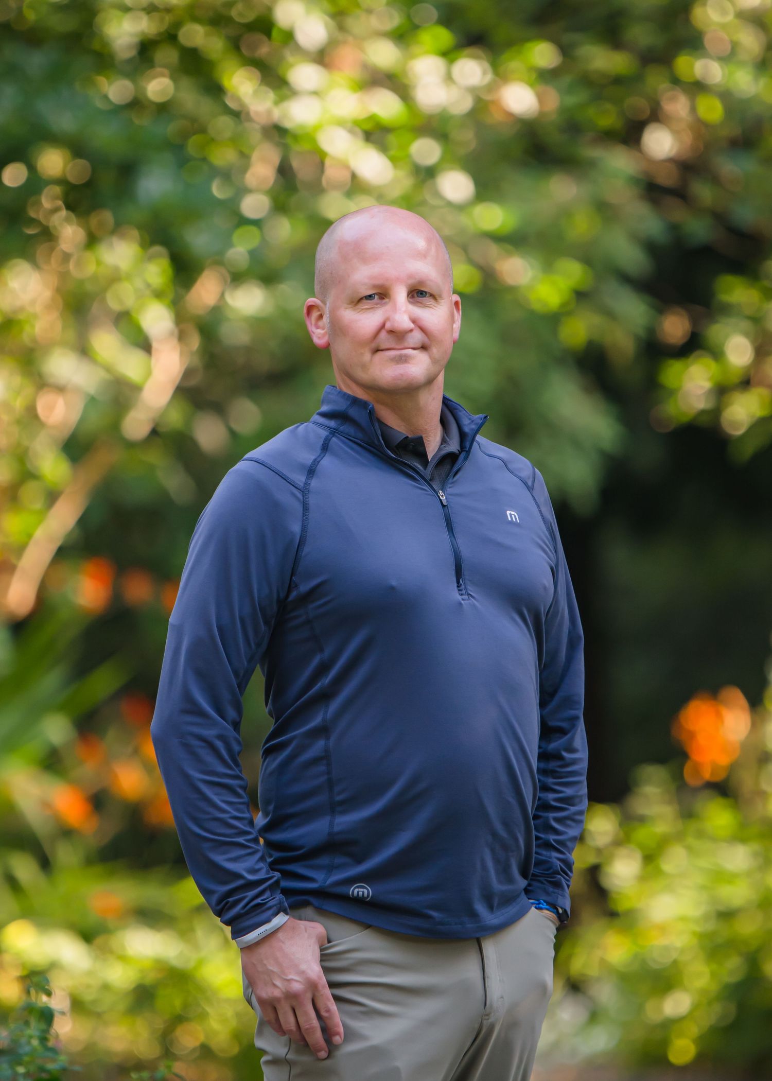 Man in navy quarter-zip pullover poses against blurred green background during a corporate Headshot session in Maple Valley, WA