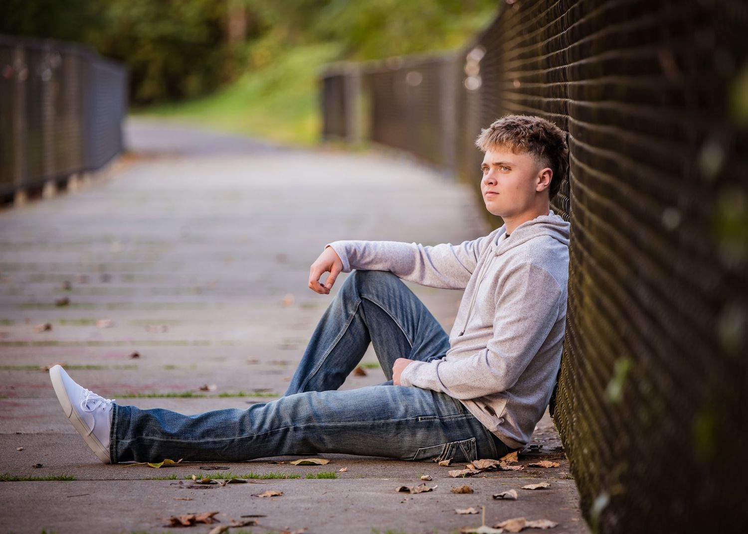 Tahoma senior relaxing on paved trail surrounded by natural scenery during senior photos