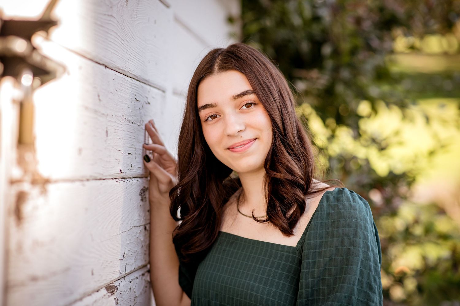 Portrait session against white wall with natural lighting and greenery during a senior session in Troutdale, OR
