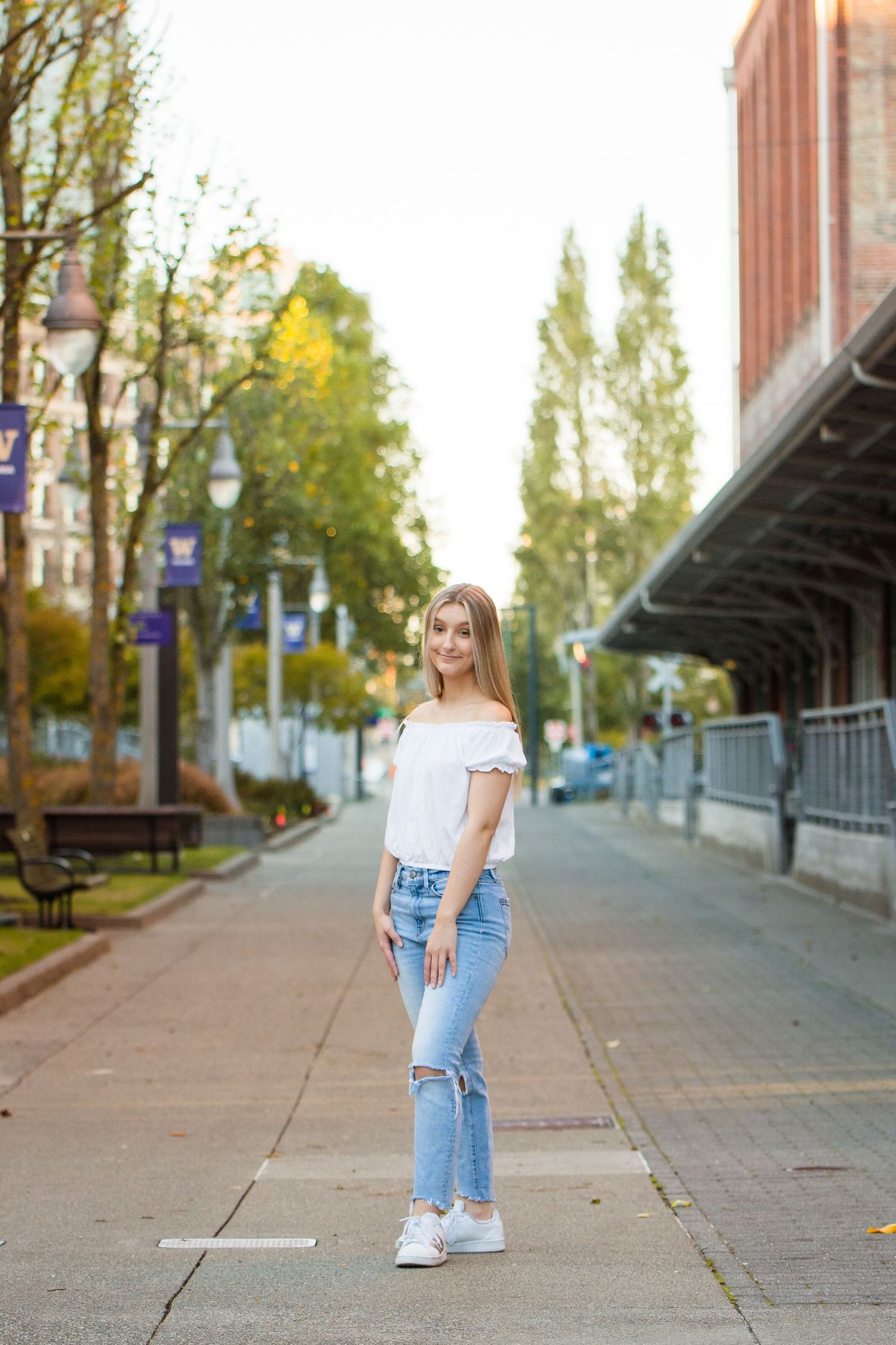 Tahoma senior in casual outfit walking along urban sidewalk during sunset during a senior photoshoot in Tacoma, WA