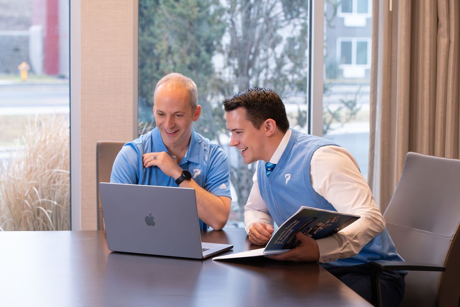 Business meeting scene in modern office with laptop and documents on conference table. Two men pose for a corporate branding session in WA