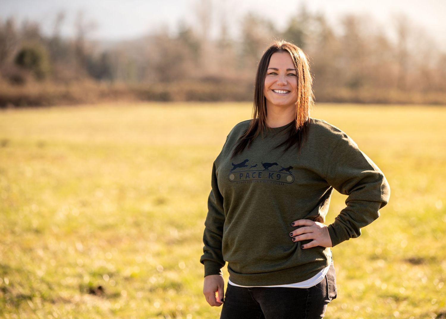 Person wearing casual green sweatshirt poses in sunlit meadow in a branding session in Enumclaw, WA