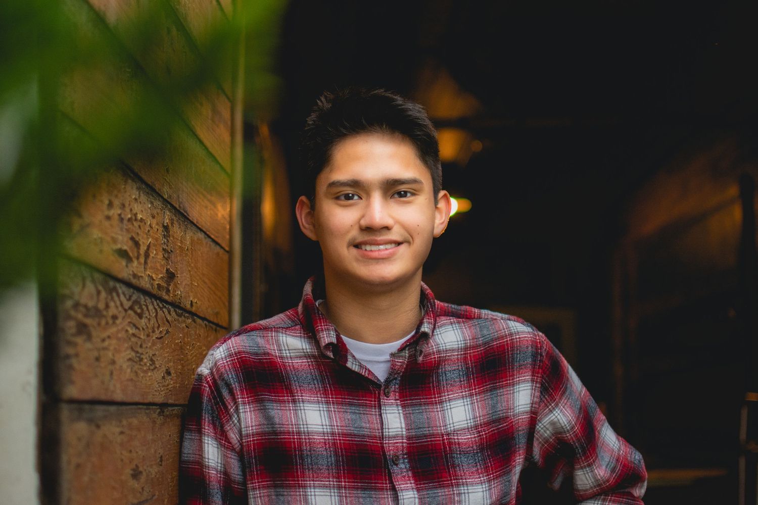 High school senior in plaid shirt photographed against dark background during a senior session in Troutdale, OR