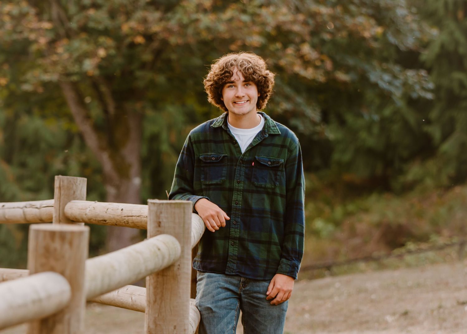 Tahoma senior standing by wooden fence railing in outdoor nature setting during a senior session in Maple Valley, WA