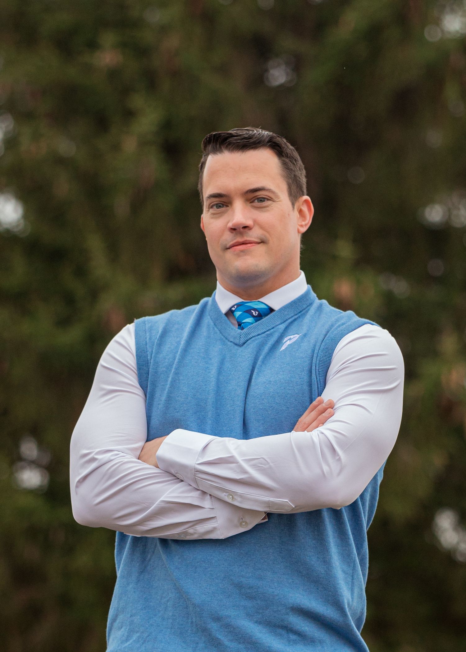 Business casual man poses for headshot wearing a blue vest and white dress shirt outdoors in Pullman, WA