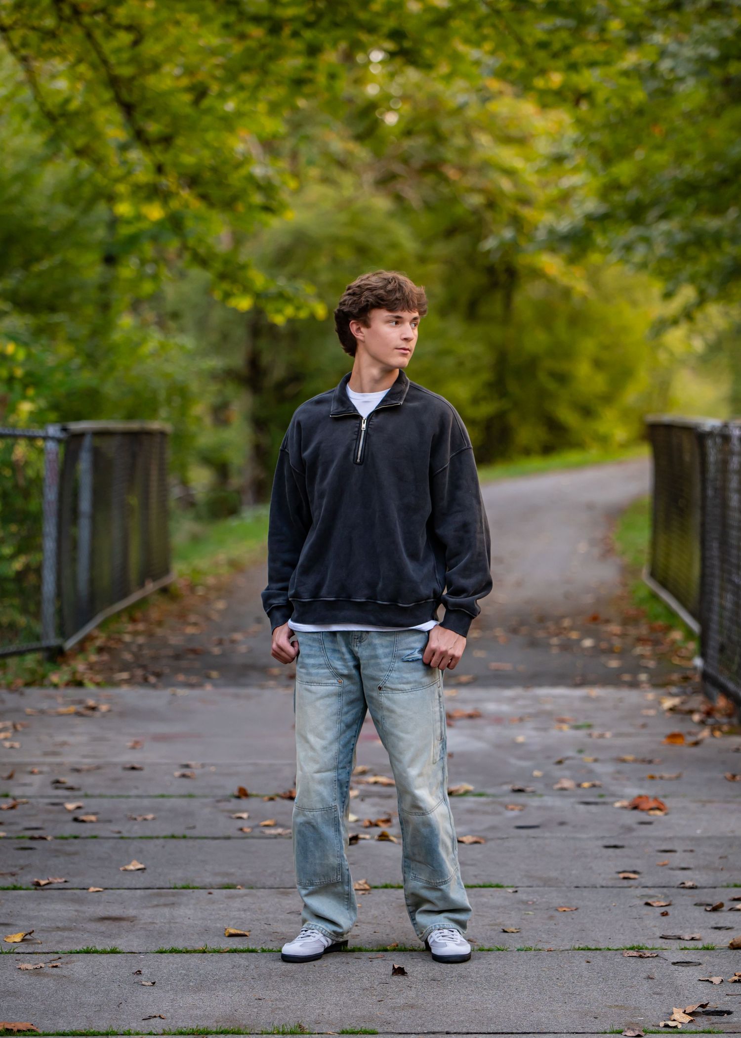 Tahoma senior in dark hoodie and jeans posing on leaf-covered pathway in a Maple Valley, WA senior photoshoot