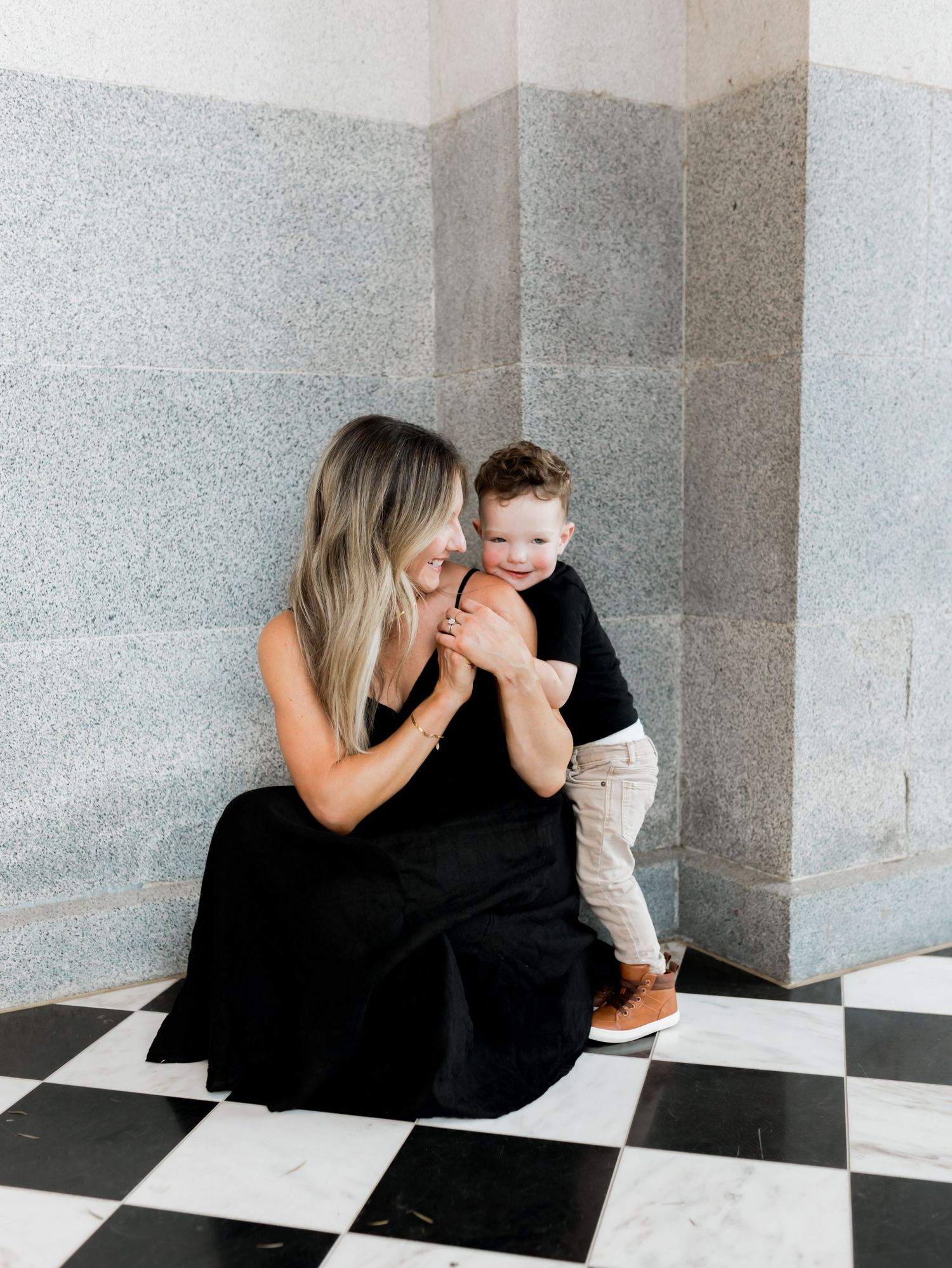 Intimate black and white portraits captured on a checkered floor showing tender family moments.
