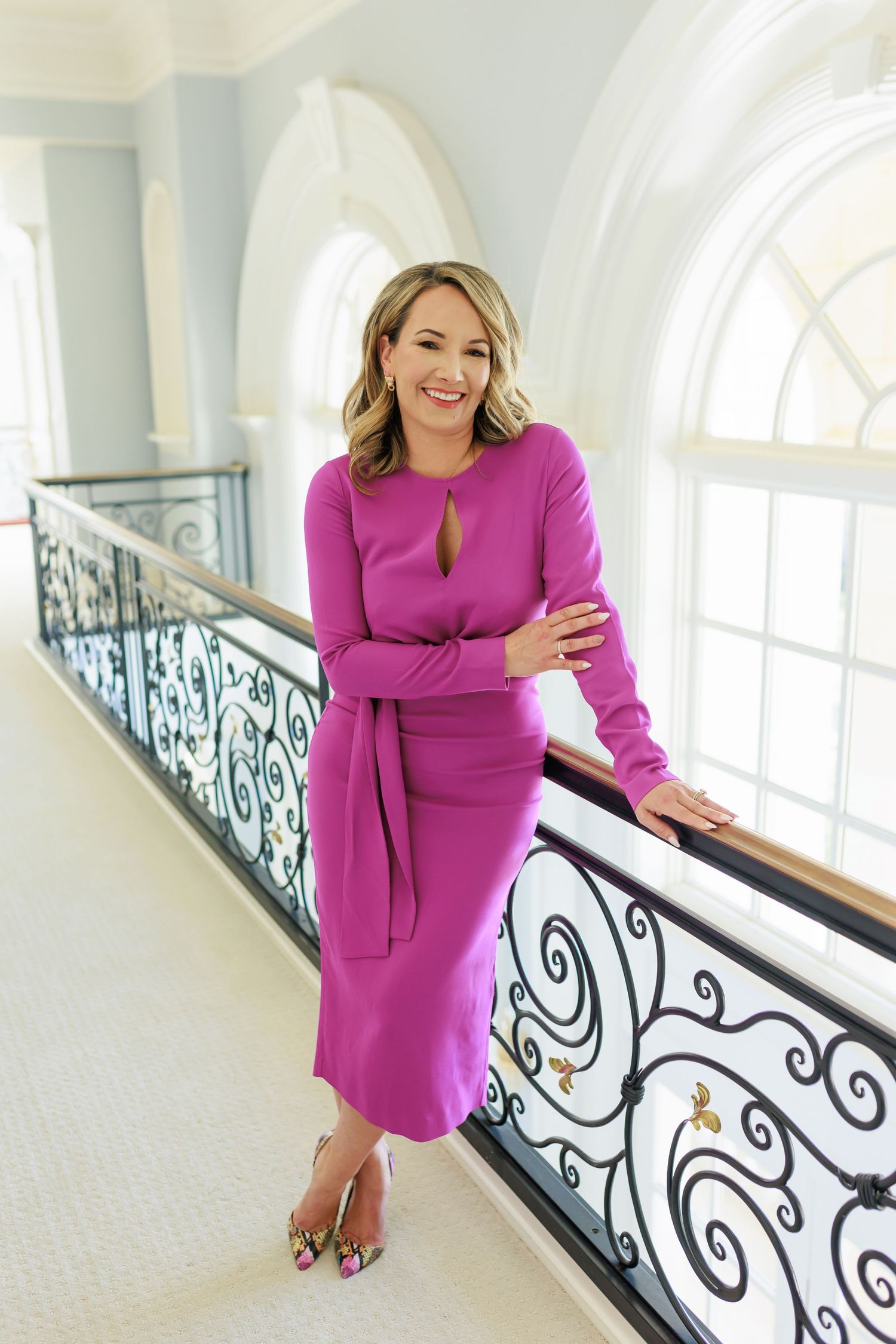 Fashion portraits on elegant staircase wearing vibrant pink dress.