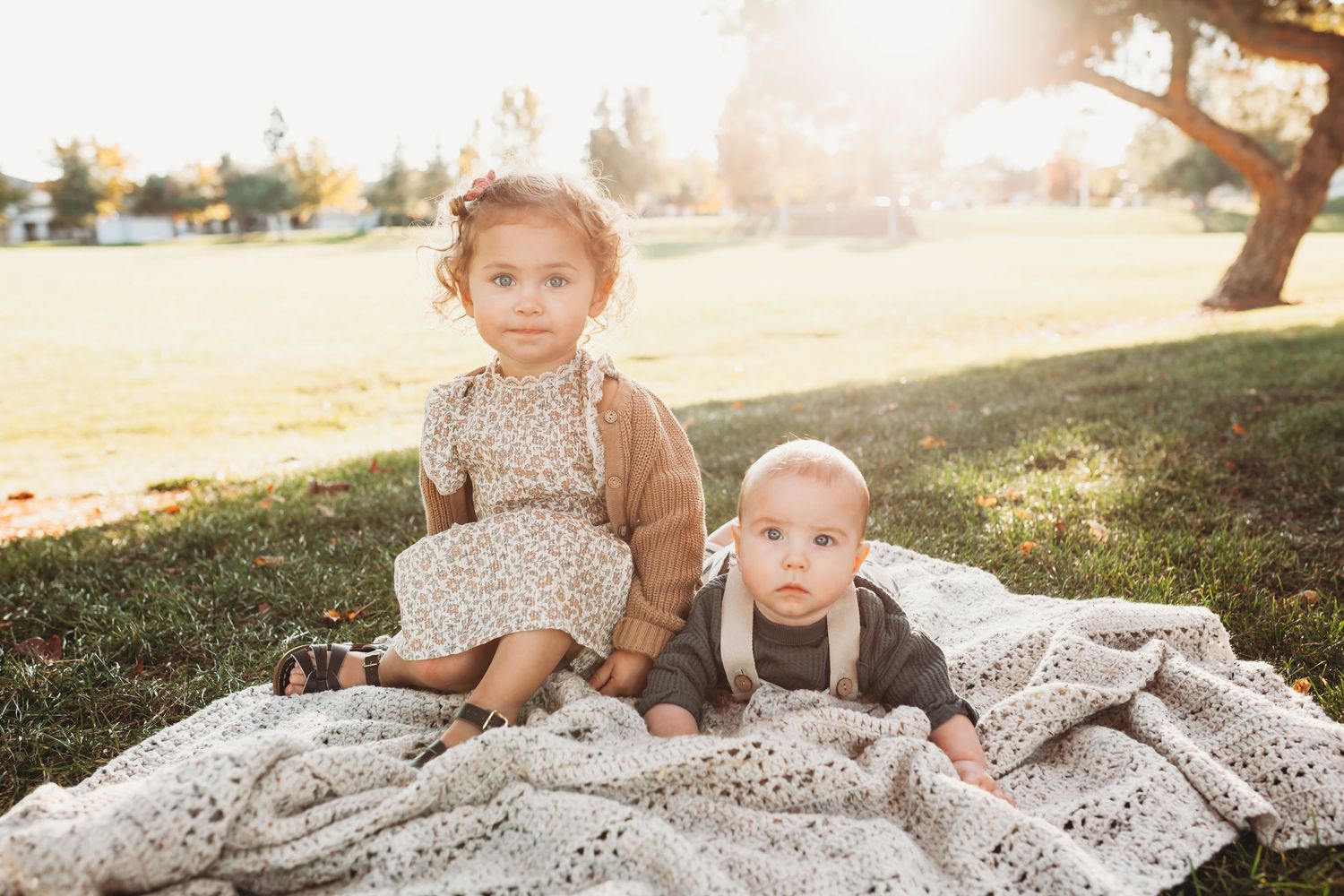 Children and family members relax on a blanket during an outdoor photo session at sunset.
