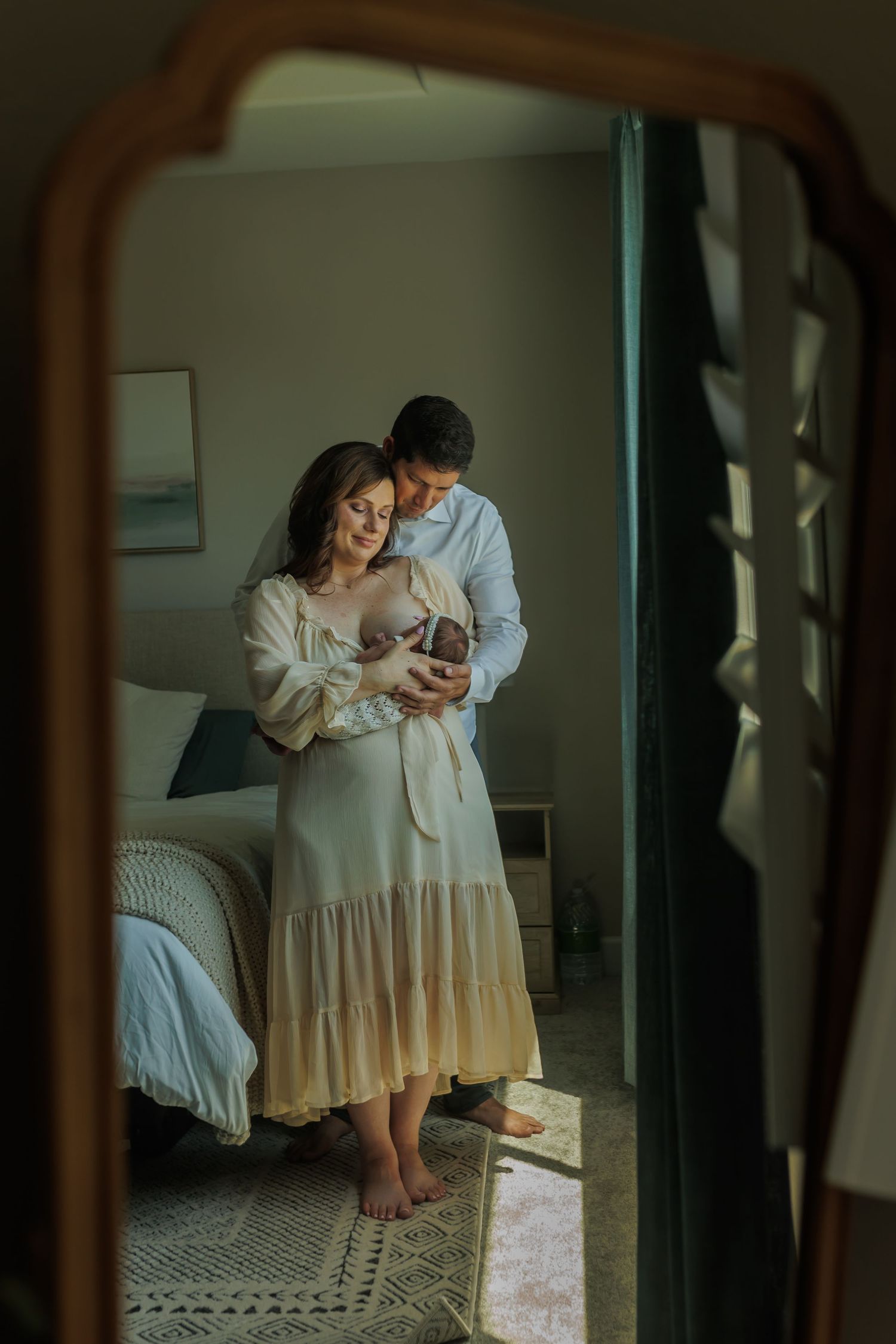 Intimate family moment with newborn captured through mirror reflection.