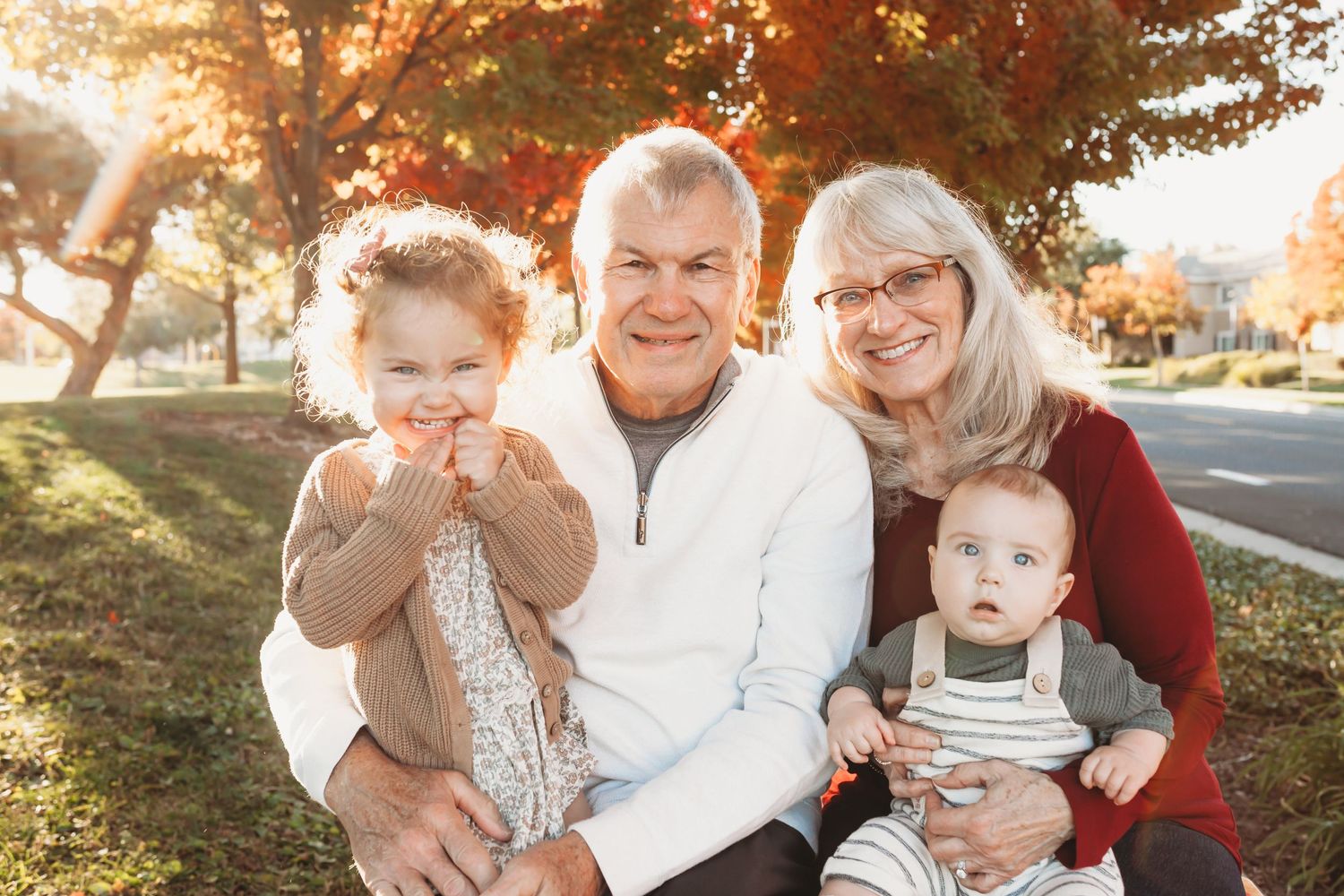 Family gathering outdoors during autumn with warm sunlight filtering through trees.