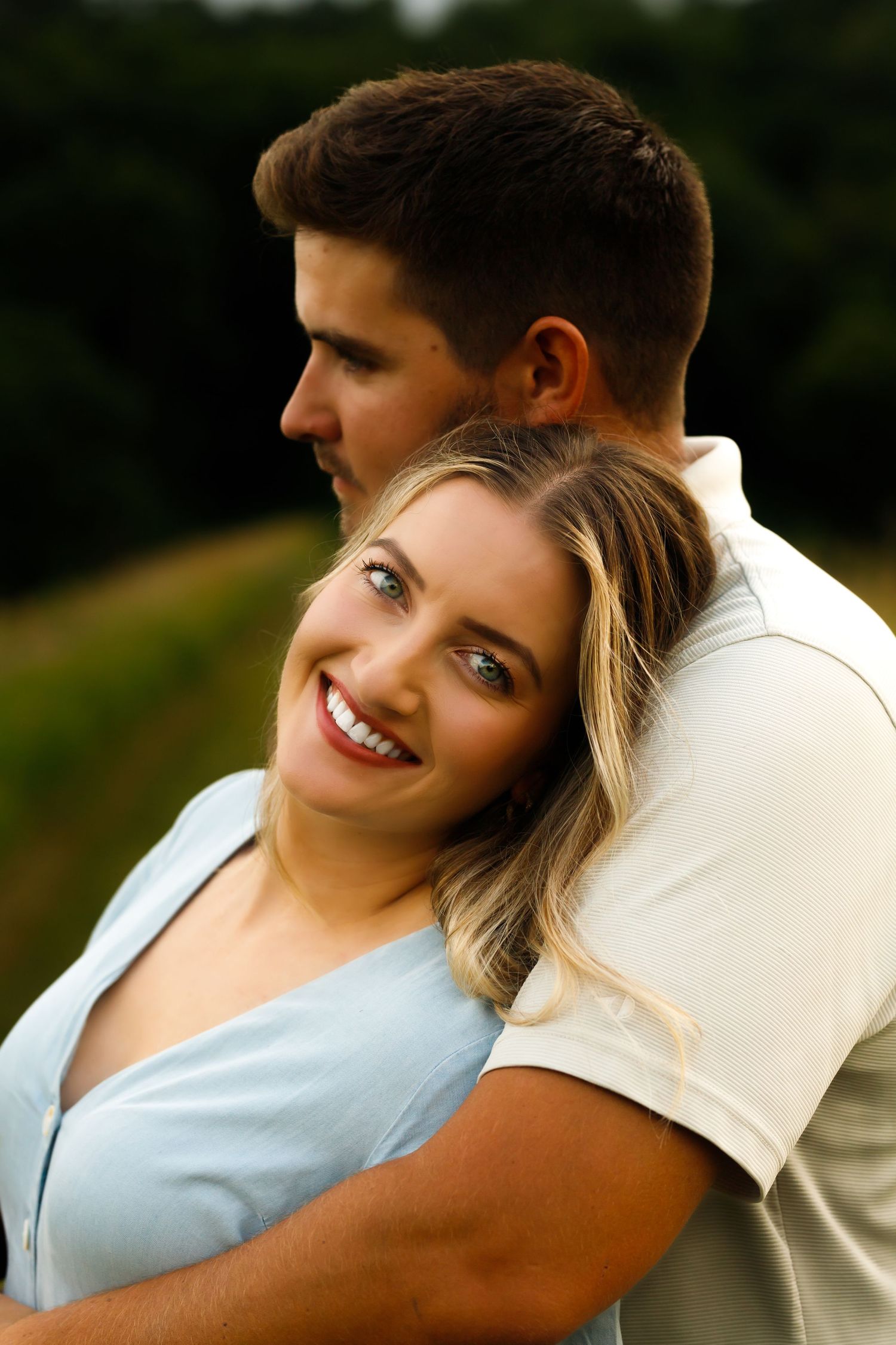 Intimate couple portrait session in a lush green field during golden hour.