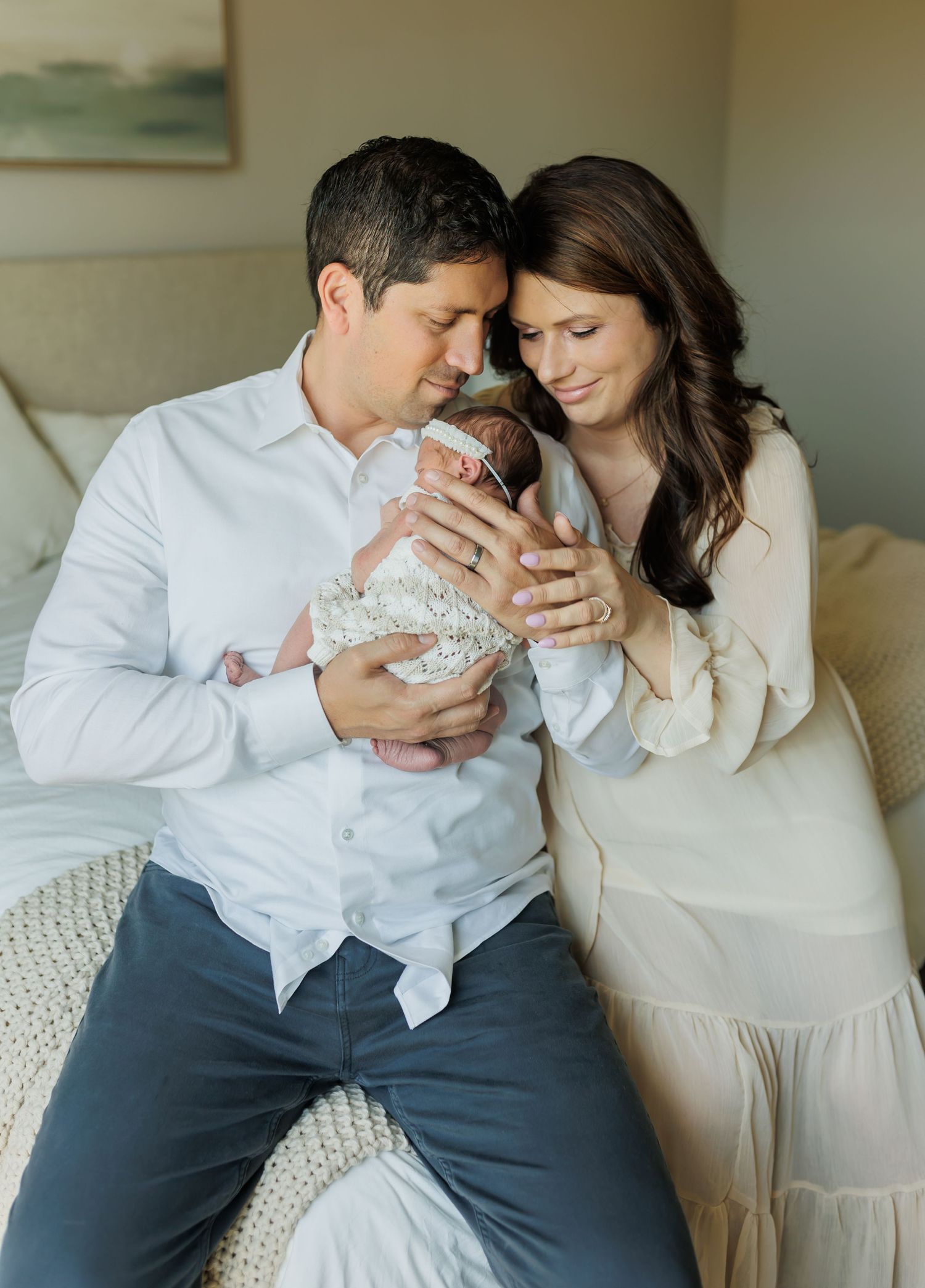 Intimate indoor family portrait session with newborn on white couch.
