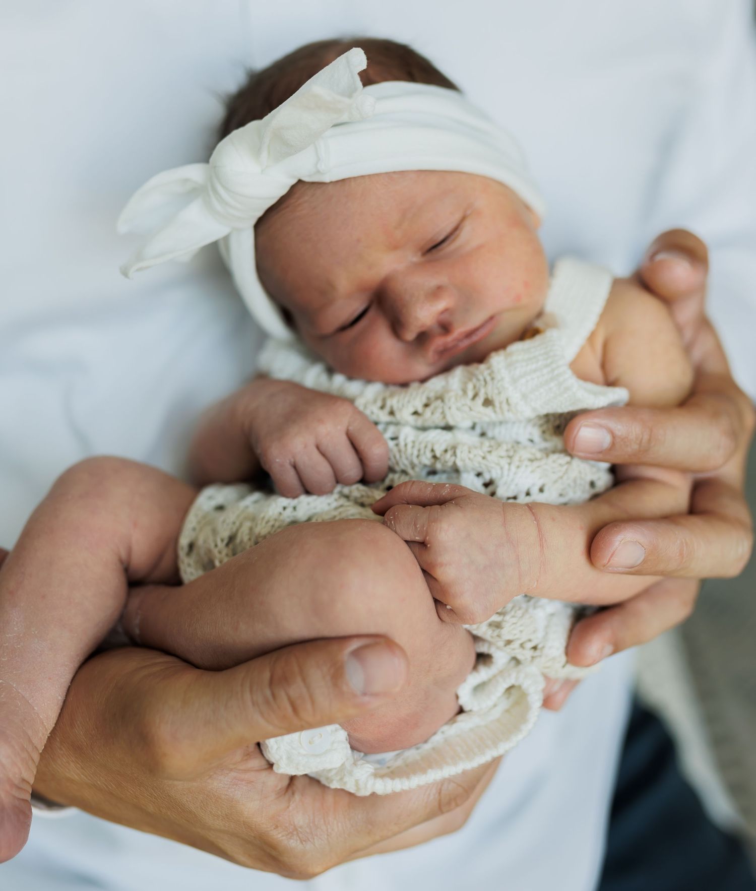 Close-up of tiny newborn baby being cradled in gentle hands.