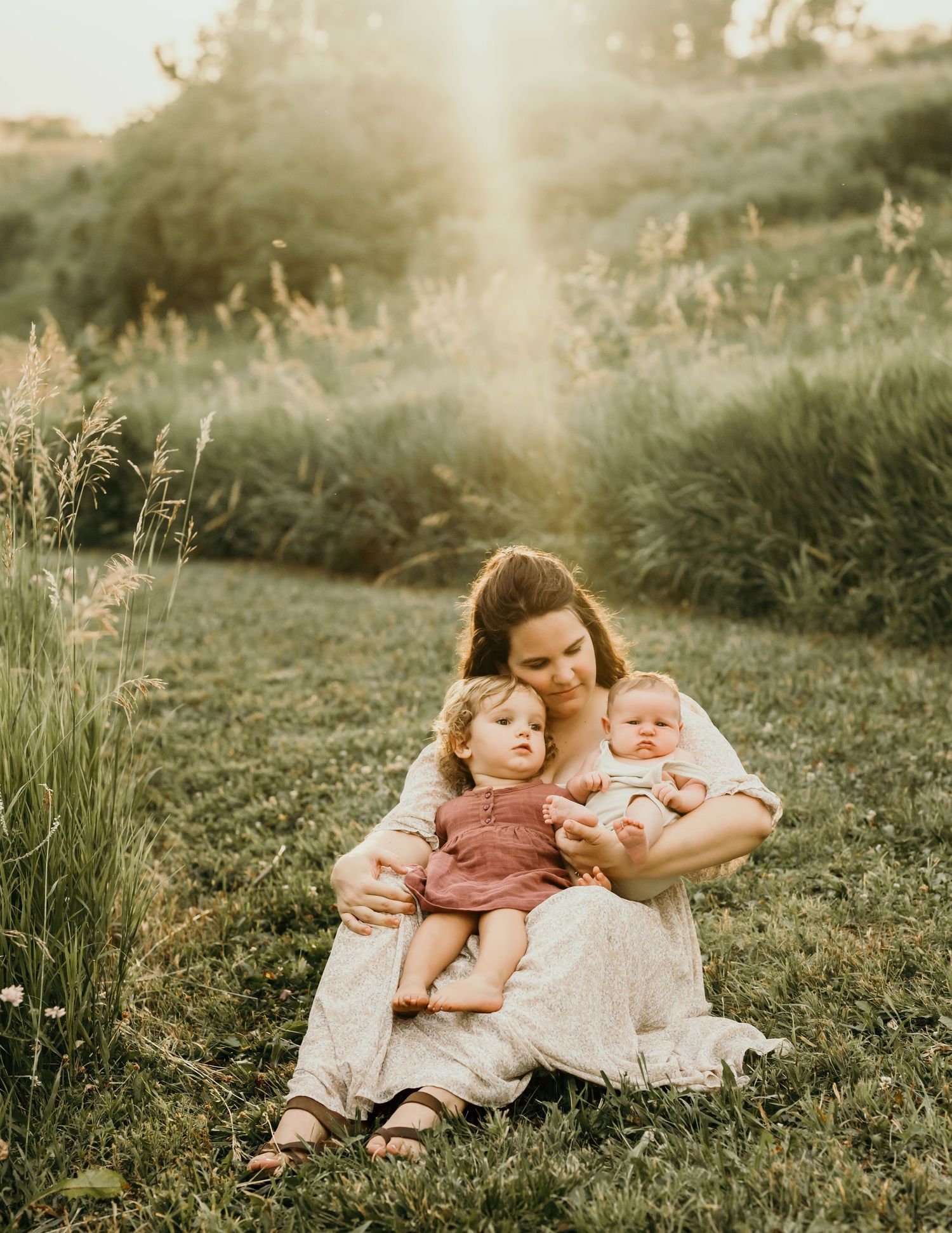 Intimate family portrait session in a natural outdoor setting with golden sunset lighting.