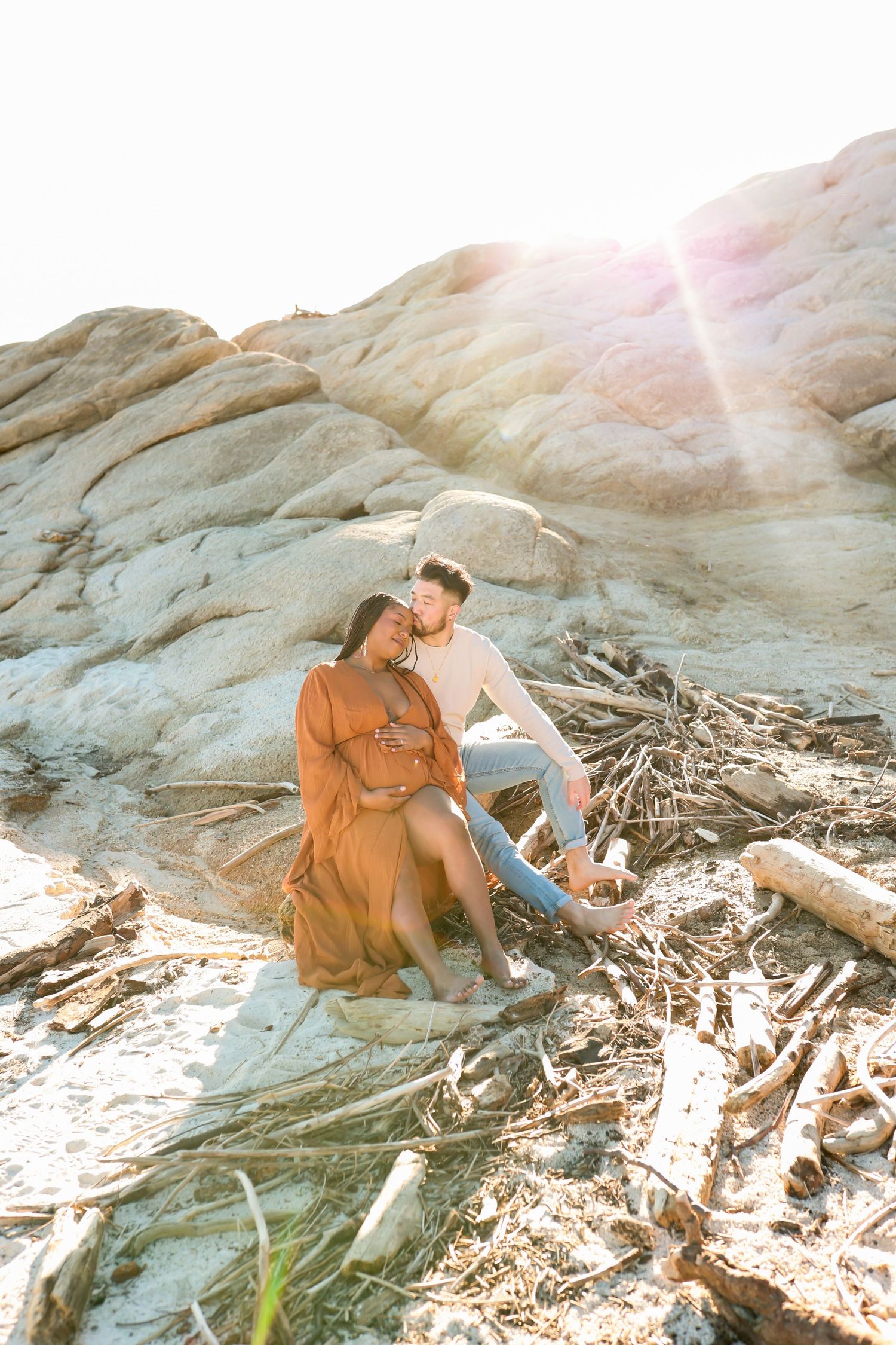 Figure in earth-toned dress explores rocky coastal landscape at golden hour.