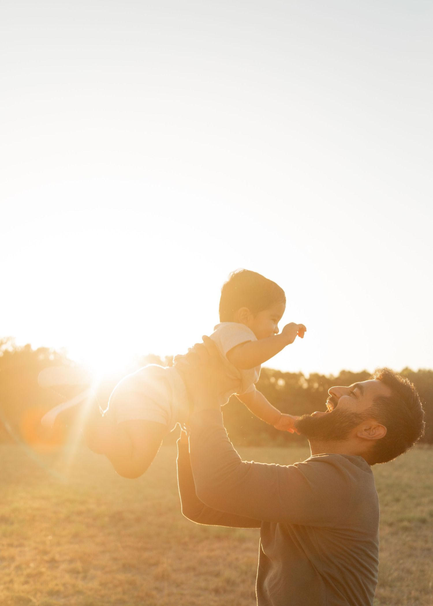 Father holding up his two year old boy with the sun setting in the background. Perth, WA