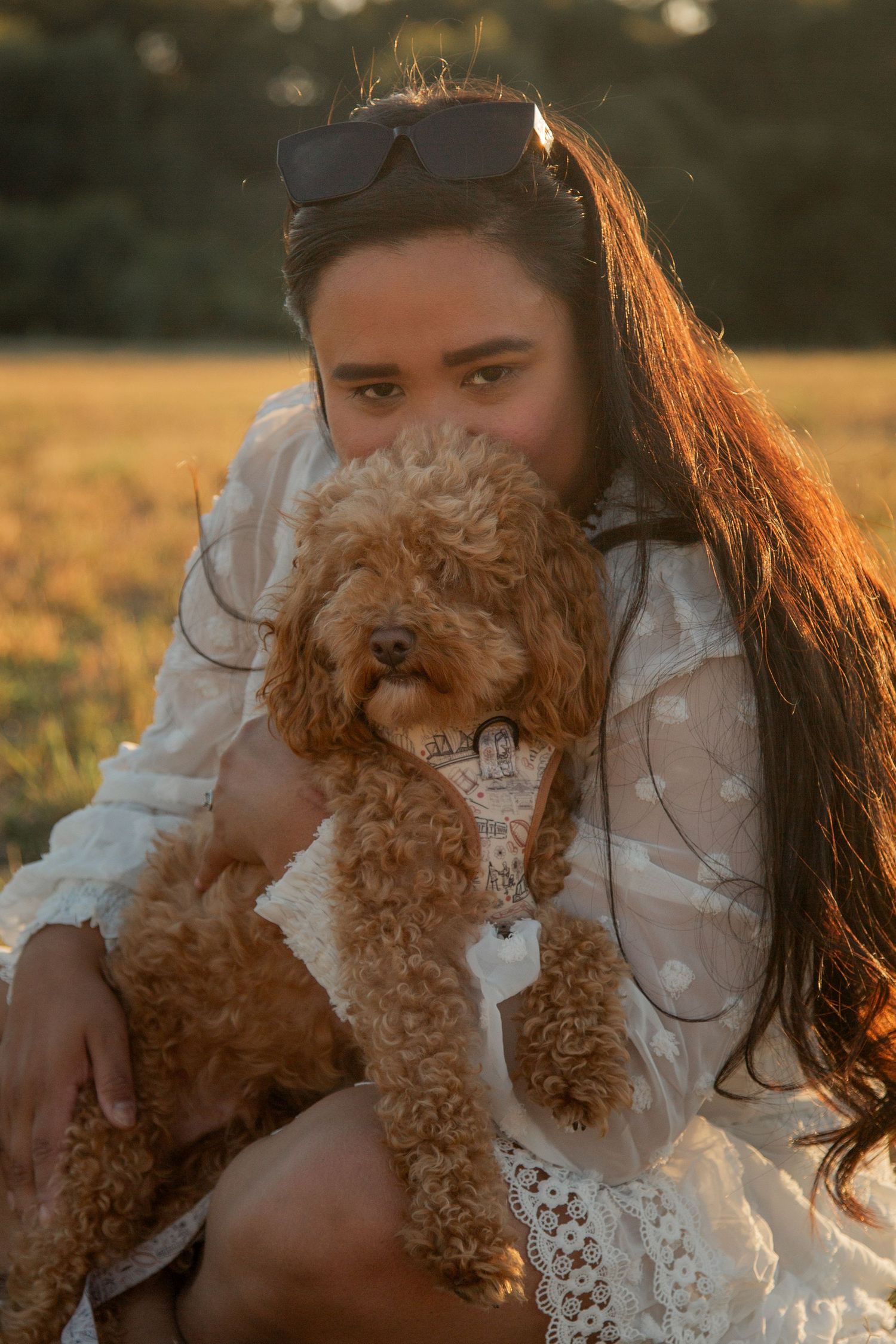 Woman in a field with her dog. Woman's face is half behind the dogs face.