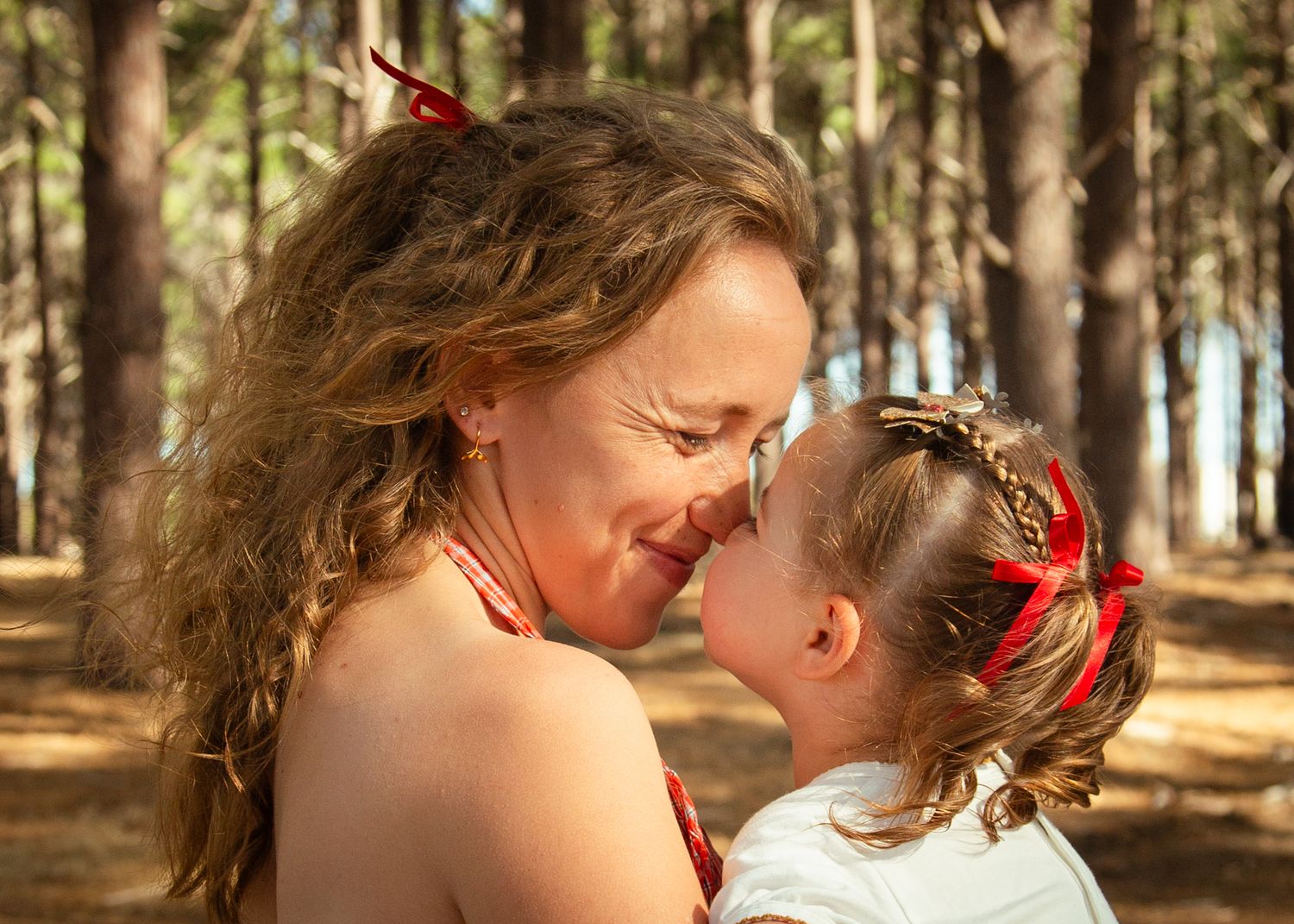 Mum and child laughing and touching nose to nose in the woods.