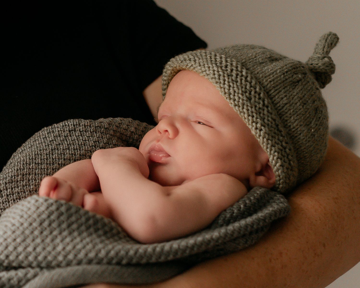 Newborn baby in his mothers arms. Dressed in green.