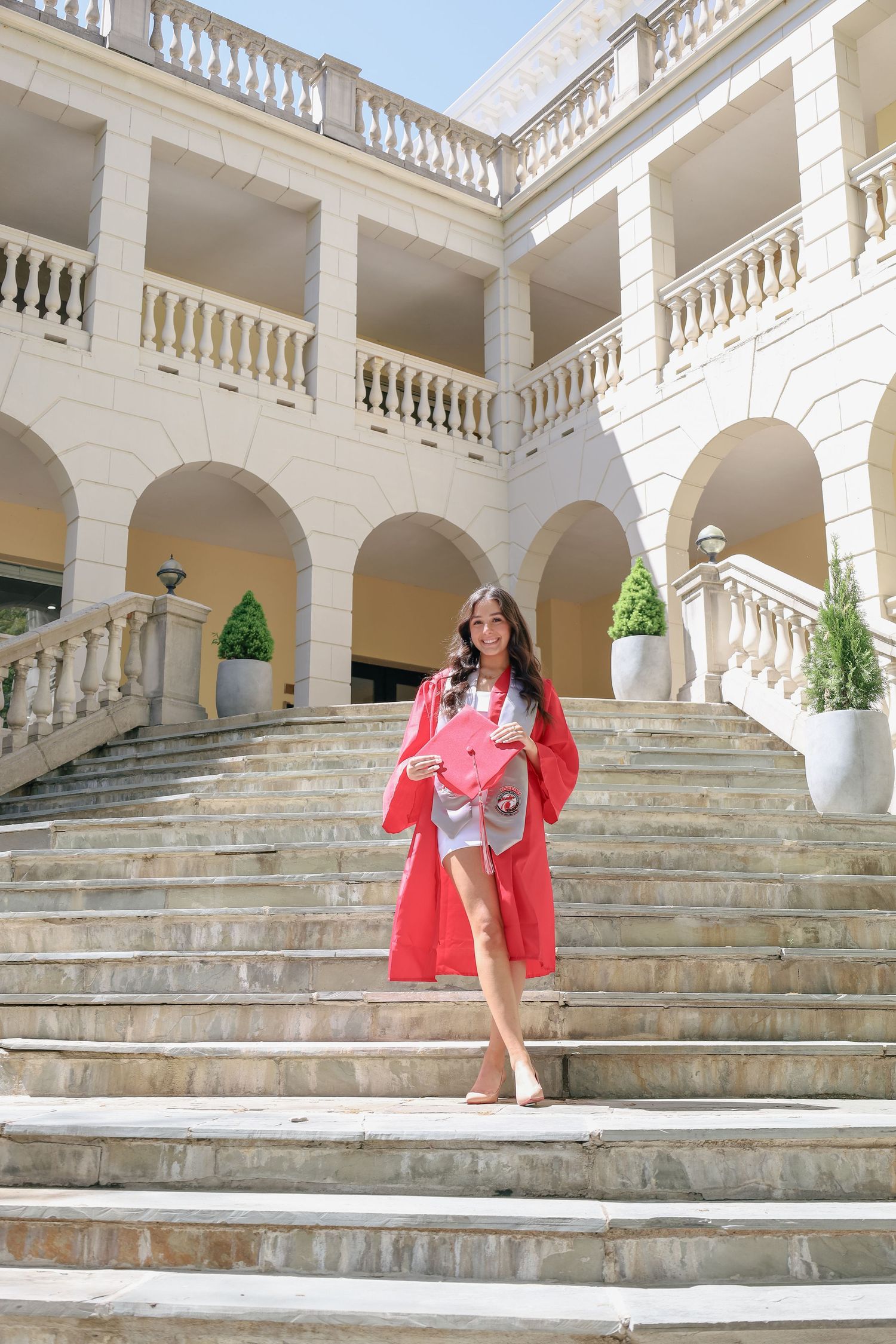 Series showing someone in red descending grand white marble steps with columns.