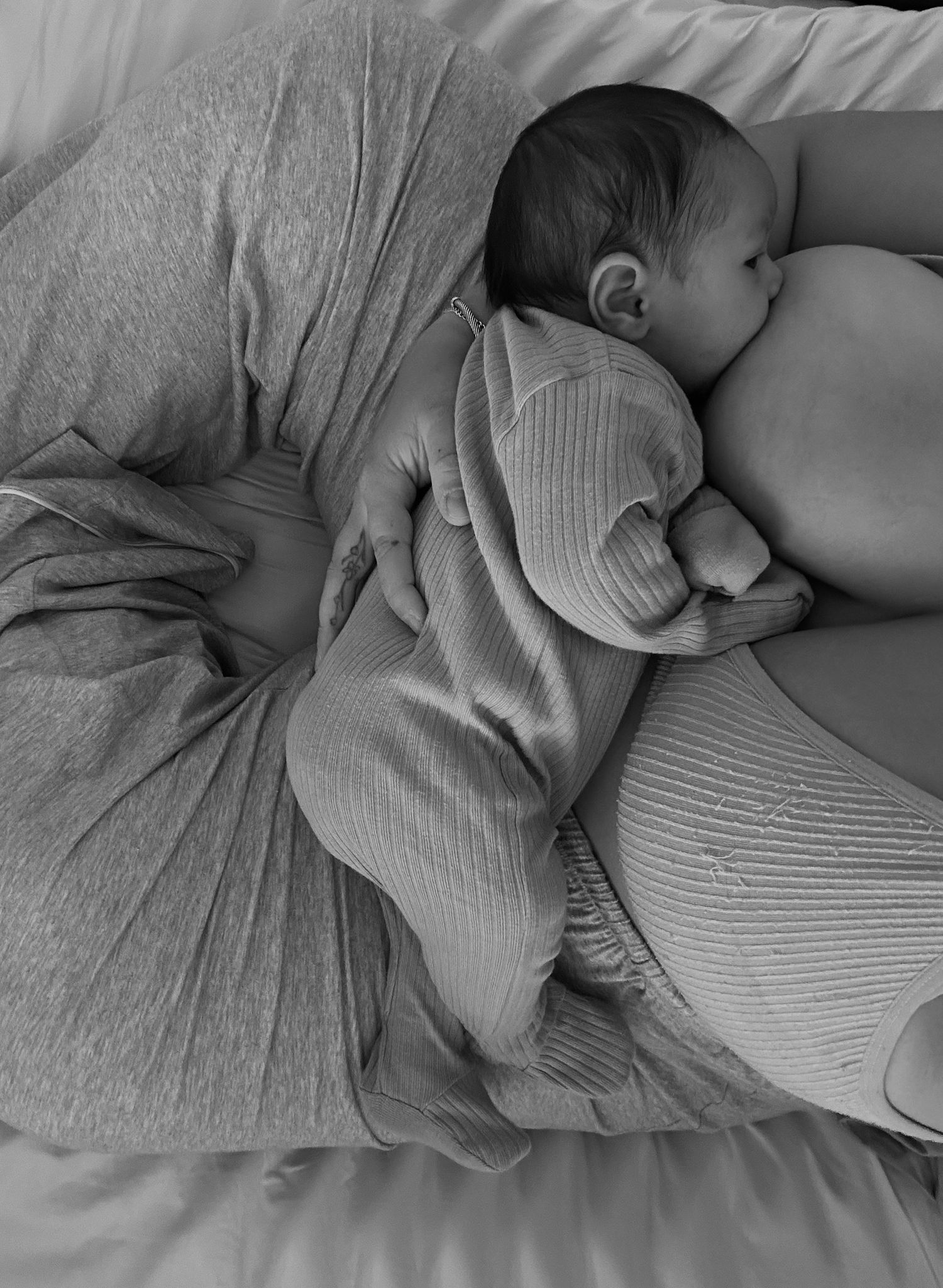 Peaceful sleeping baby in gray knit clothing on soft bedding.