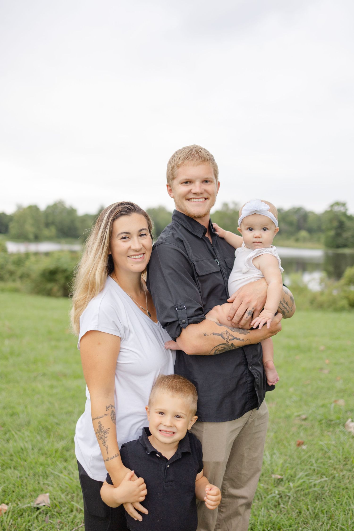 Family poses together outdoors in coordinating outfits on a grassy field during a casual portrait session.