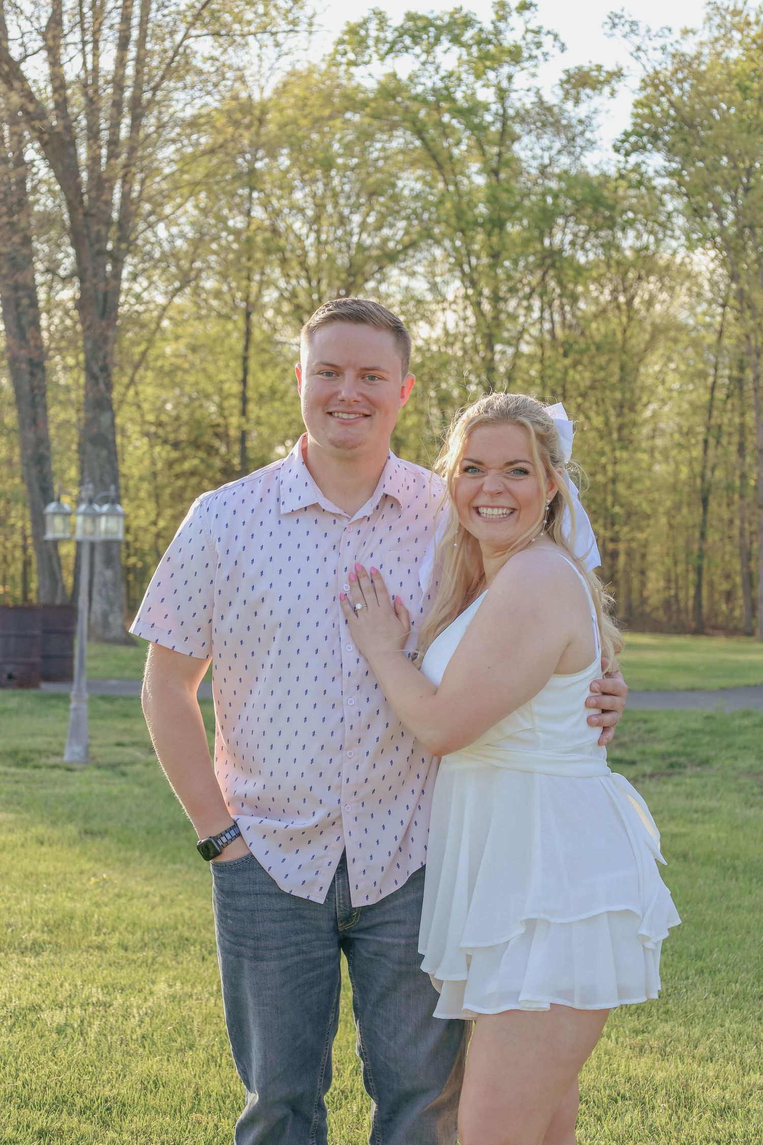 Couple poses together on grassy lawn during spring photoshoot.