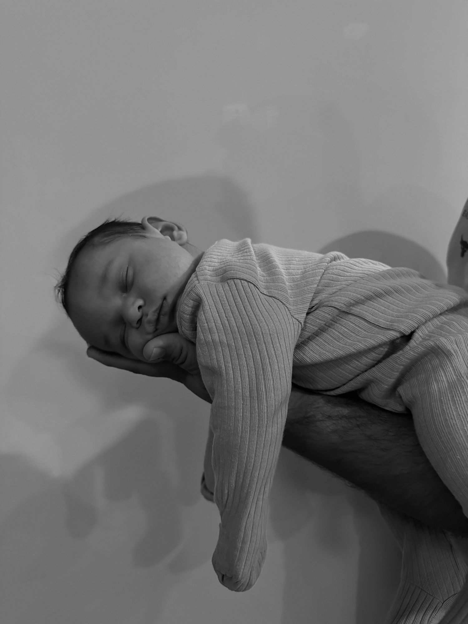 Side view of sleeping baby in ribbed onesie on gray bedding.