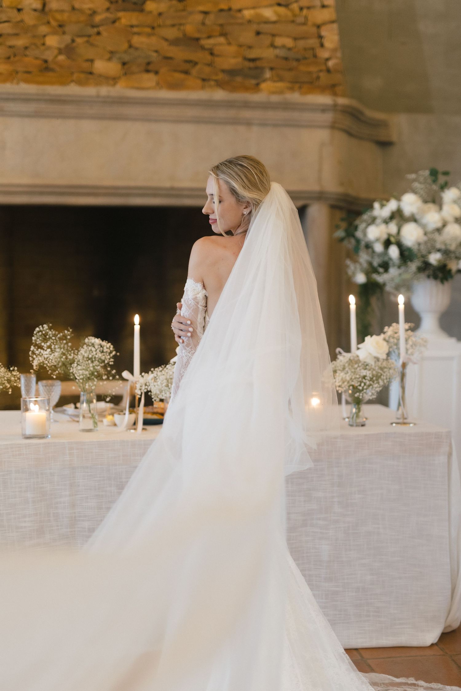 Elegant bridal portrait showcasing a flowing veil and train against candlelit reception decor.