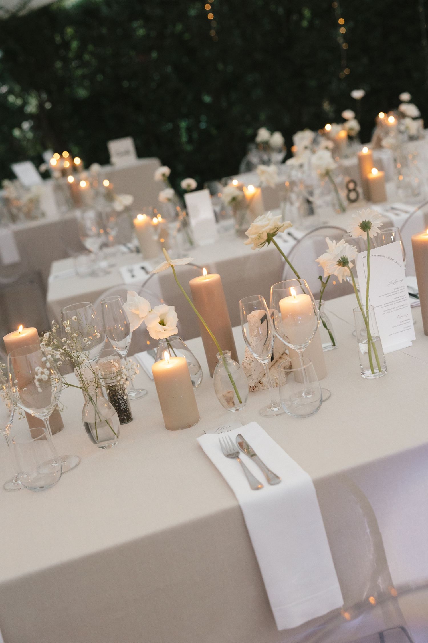 Romantic wedding reception table with glowing candles and delicate floral centerpieces.