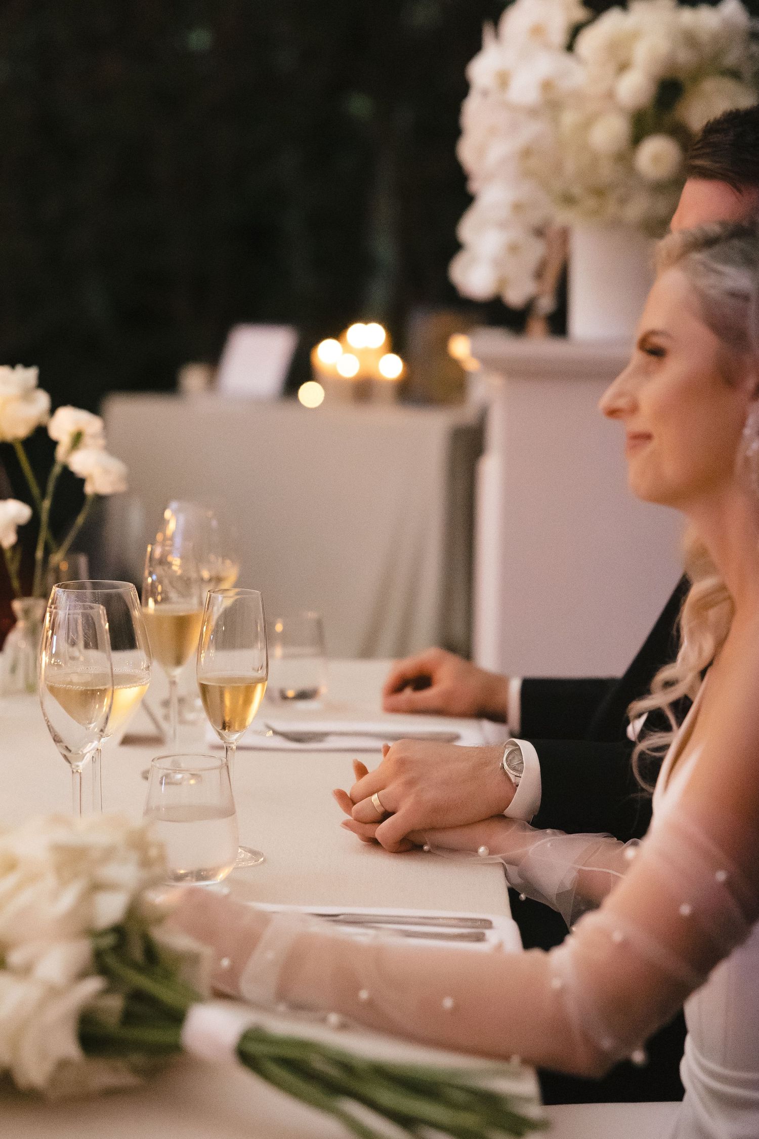 Elegant wedding reception table setting with champagne glasses and white floral decorations.