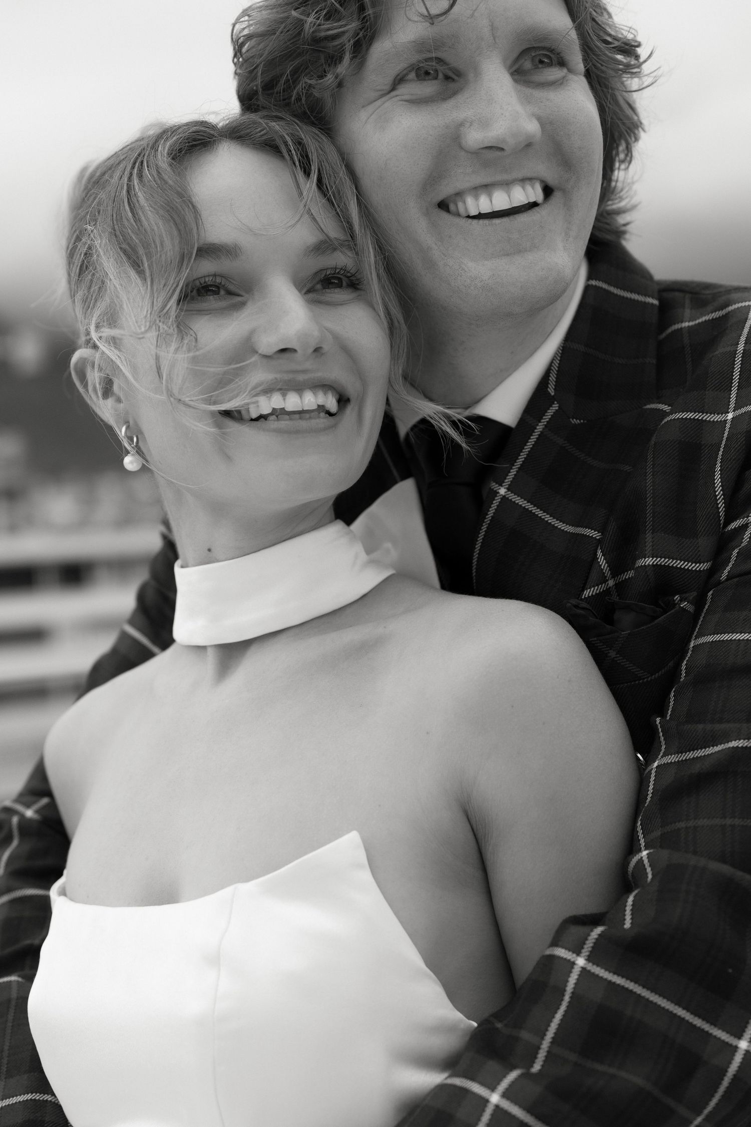 A joyful black and white wedding portrait showing a couple in formal attire.