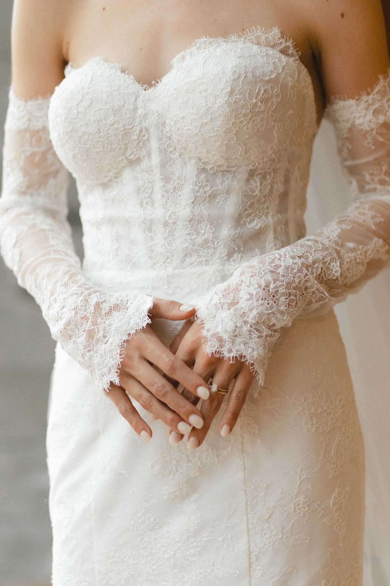 Wedding dress detail showing intricate lace sleeves and fitted corset bodice.