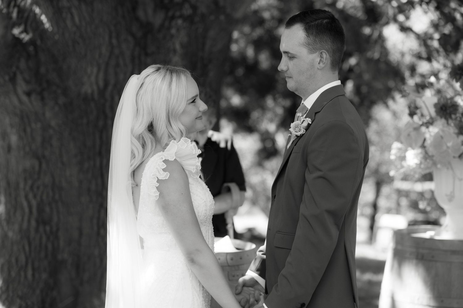 Black and white portrait of a couple exchanging vows during their outdoor wedding ceremony.