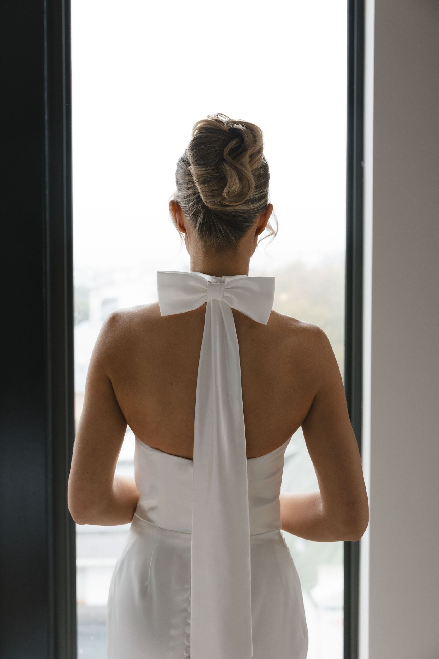 Back view of an elegant white halter wedding dress with a bow detail at the neckline.
