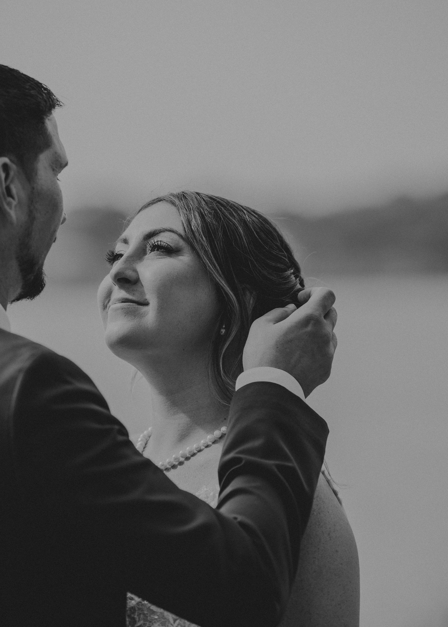 Black and white wedding photo capturing an intimate moment as couple shares a tender interaction together.
