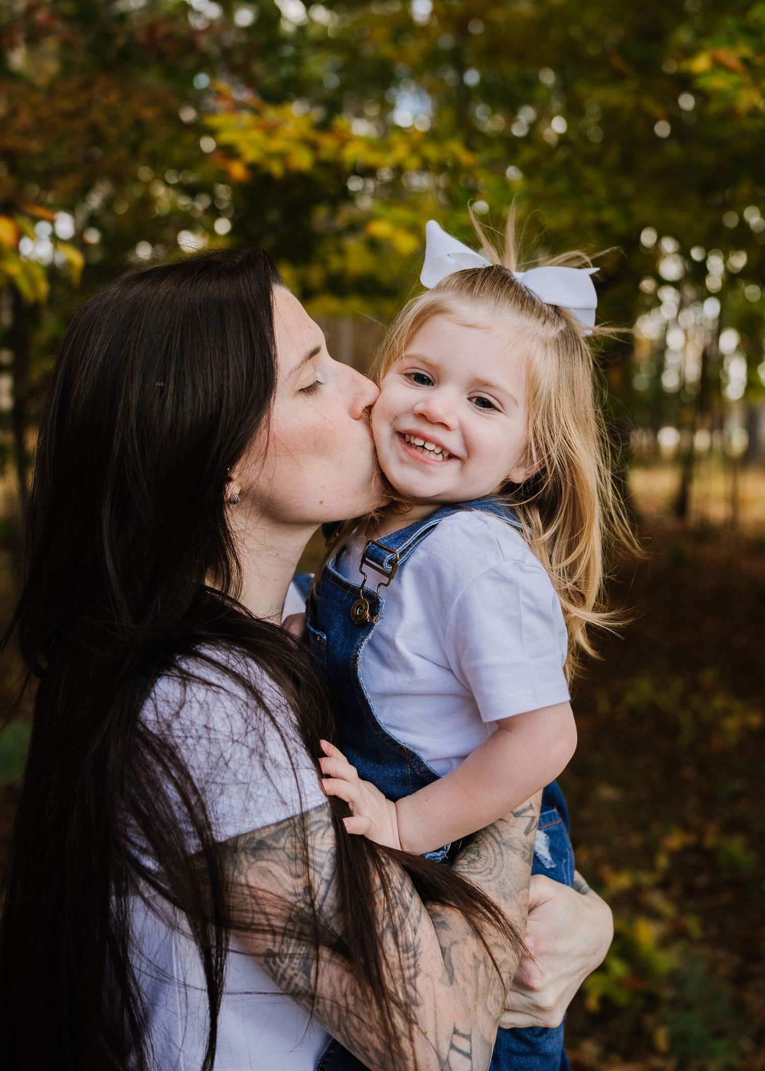 A tender moment shared between parent and child outdoors with autumn trees in the background.